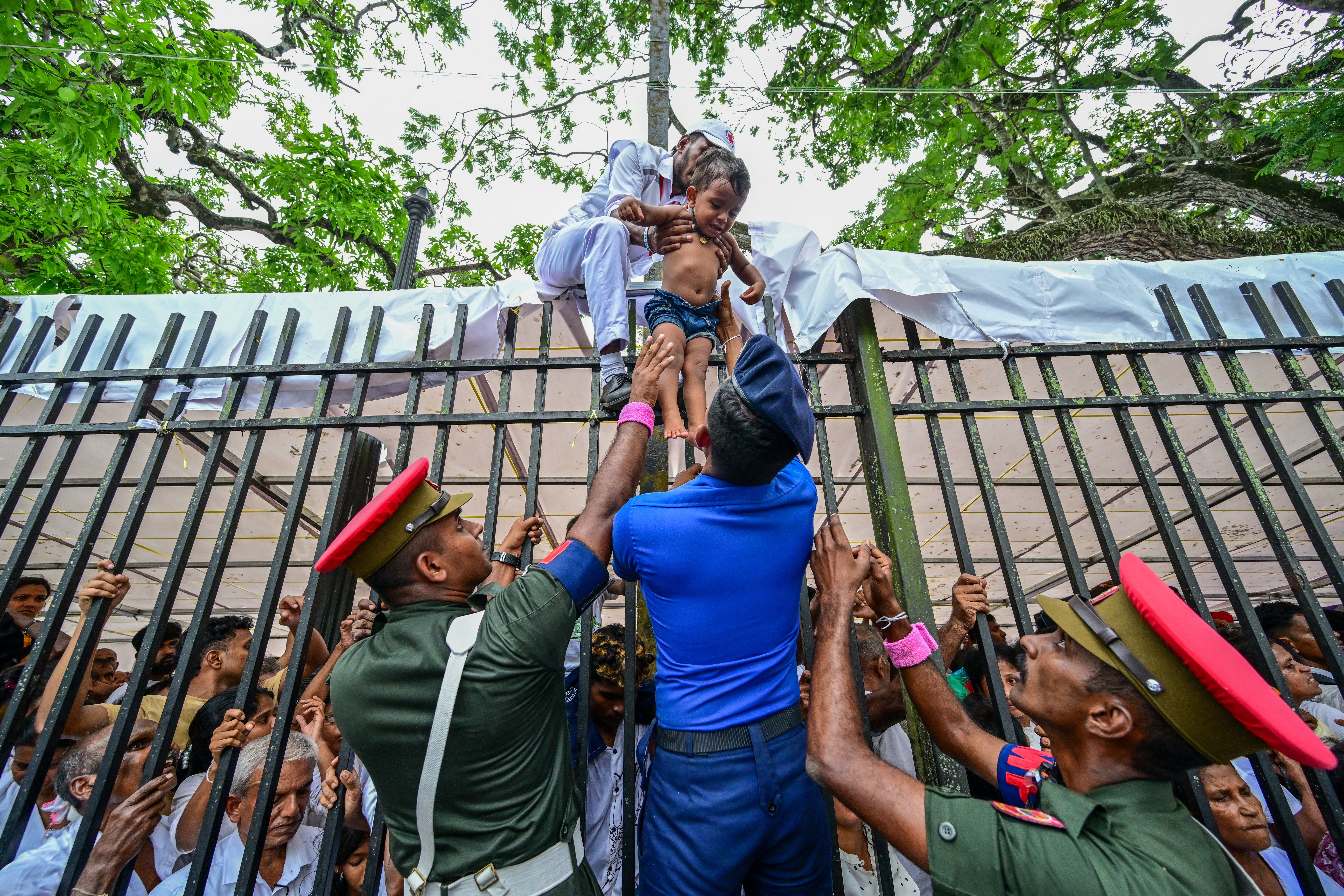 Military officials help devotees cross a fence to avoid chaos during a gathering for a public exhibition at the Temple of the Sacred Tooth in Kandy on 18 April 2025