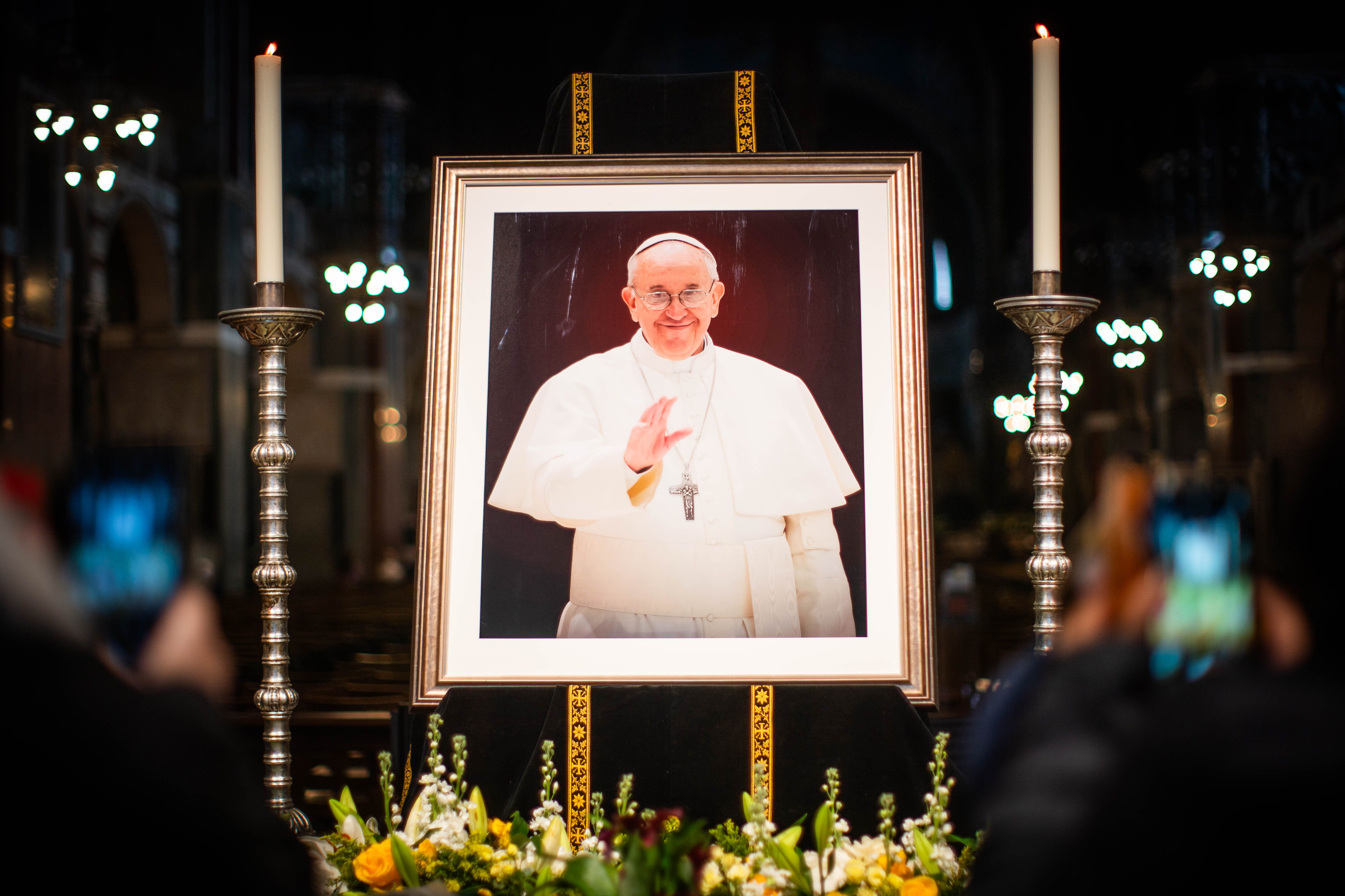 Flowers are placed in front of a picture of Pope Francis at Westminster Cathedral in central London (James Manning/PA)