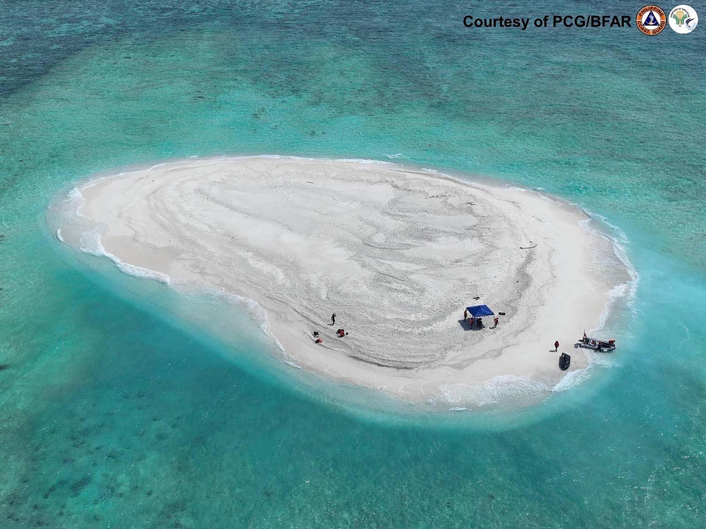 Handout photo taken on 21 March 2024 and released by the Philippine coast guard shows the country’s scientists inspecting Sandy Cay reef