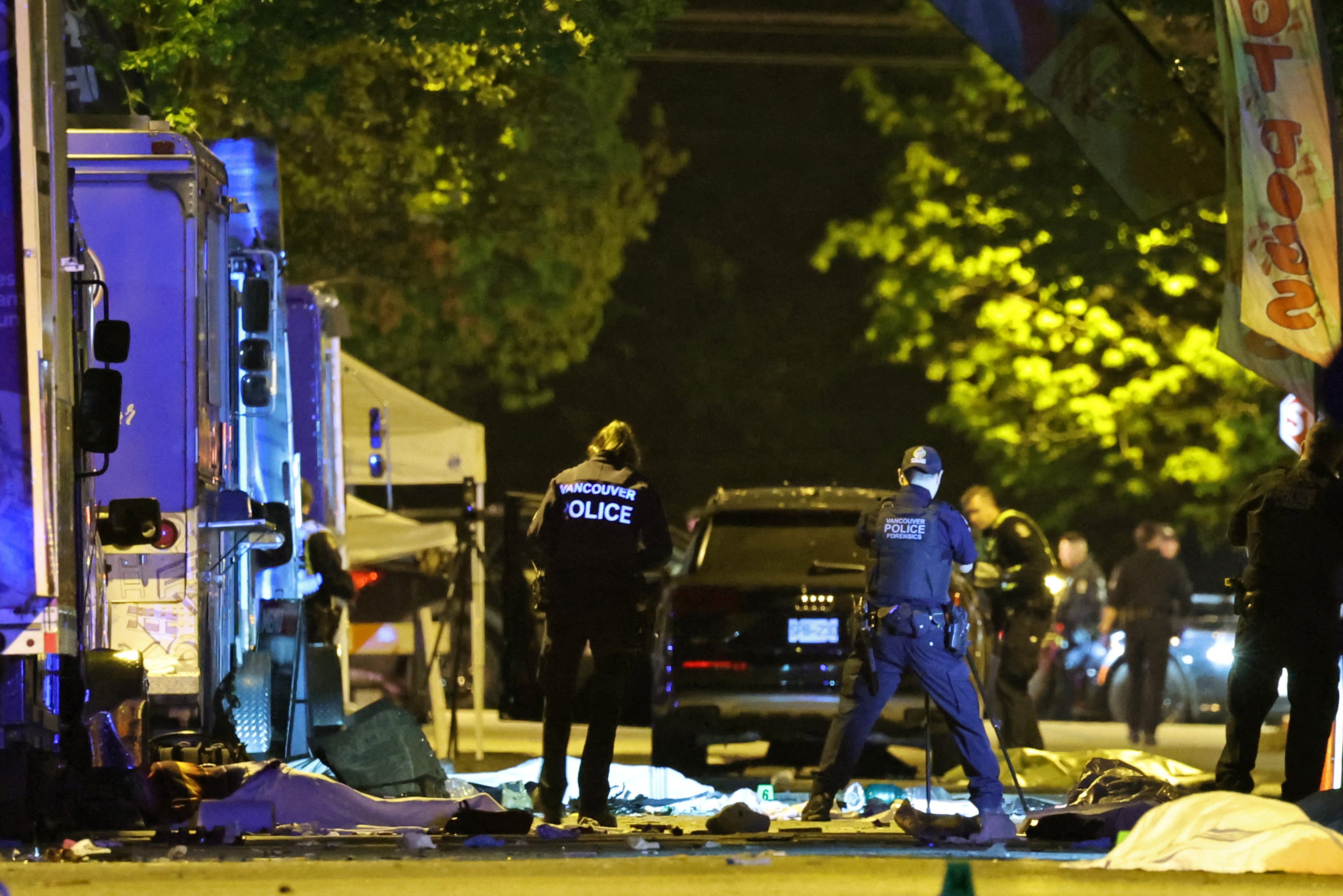 Vancouver Police forensics officers investigate the scene of a suspect vehicle and bodies of victims lying covered on the ground
