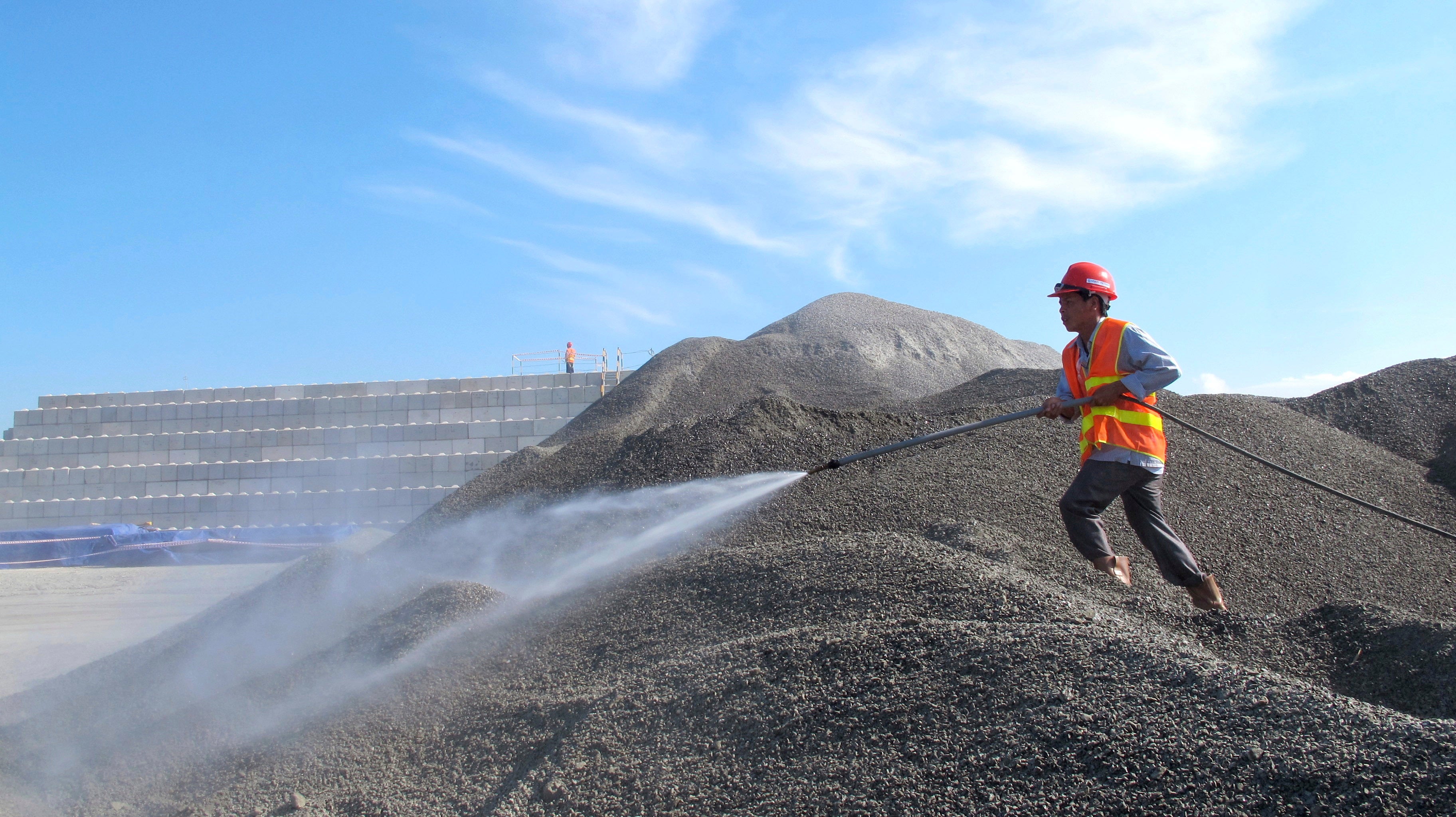 A Vietnamese worker sprays water over stones to be used in the construction of a silo for storing soil contaminated with Agent Orange dioxide at the site of a former American airbase in Da Nang
