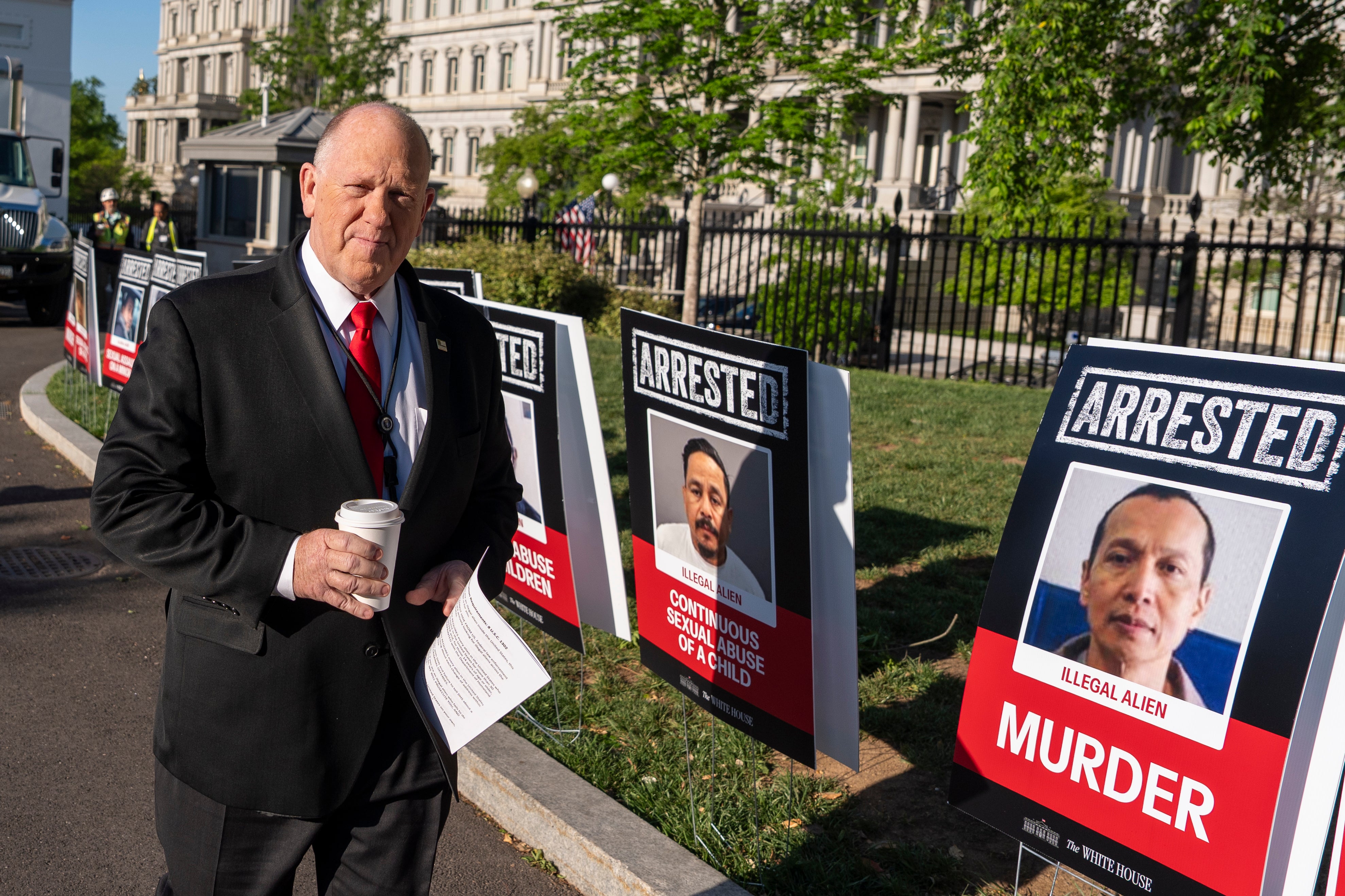 Homan outside the White House next to posters of immigrants who were arrested on criminal charges