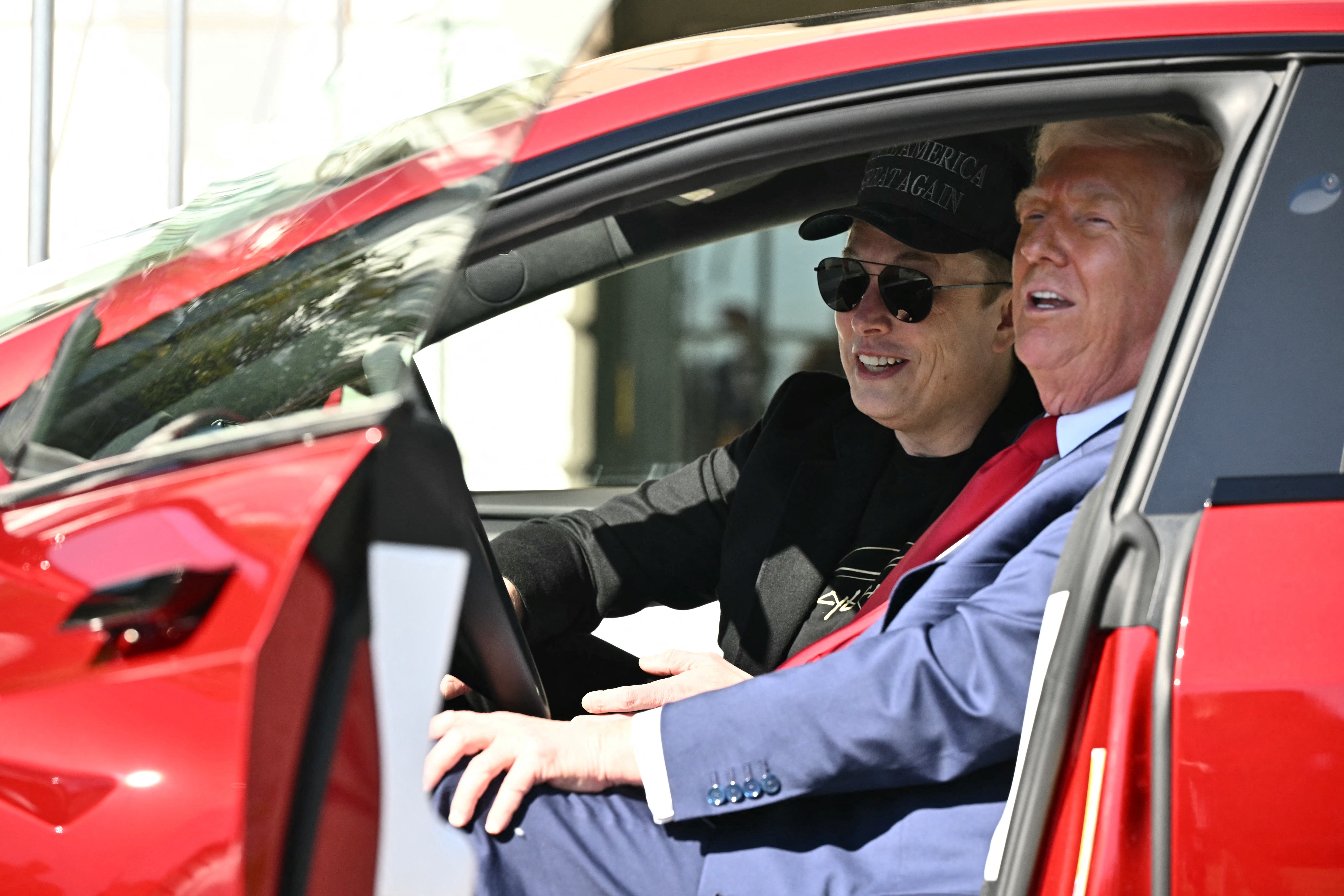 President Donald Trump and Tesla CEO Elon Musk speak to the press as they sit in a Tesla vehicle on the South Portico of the White House in March