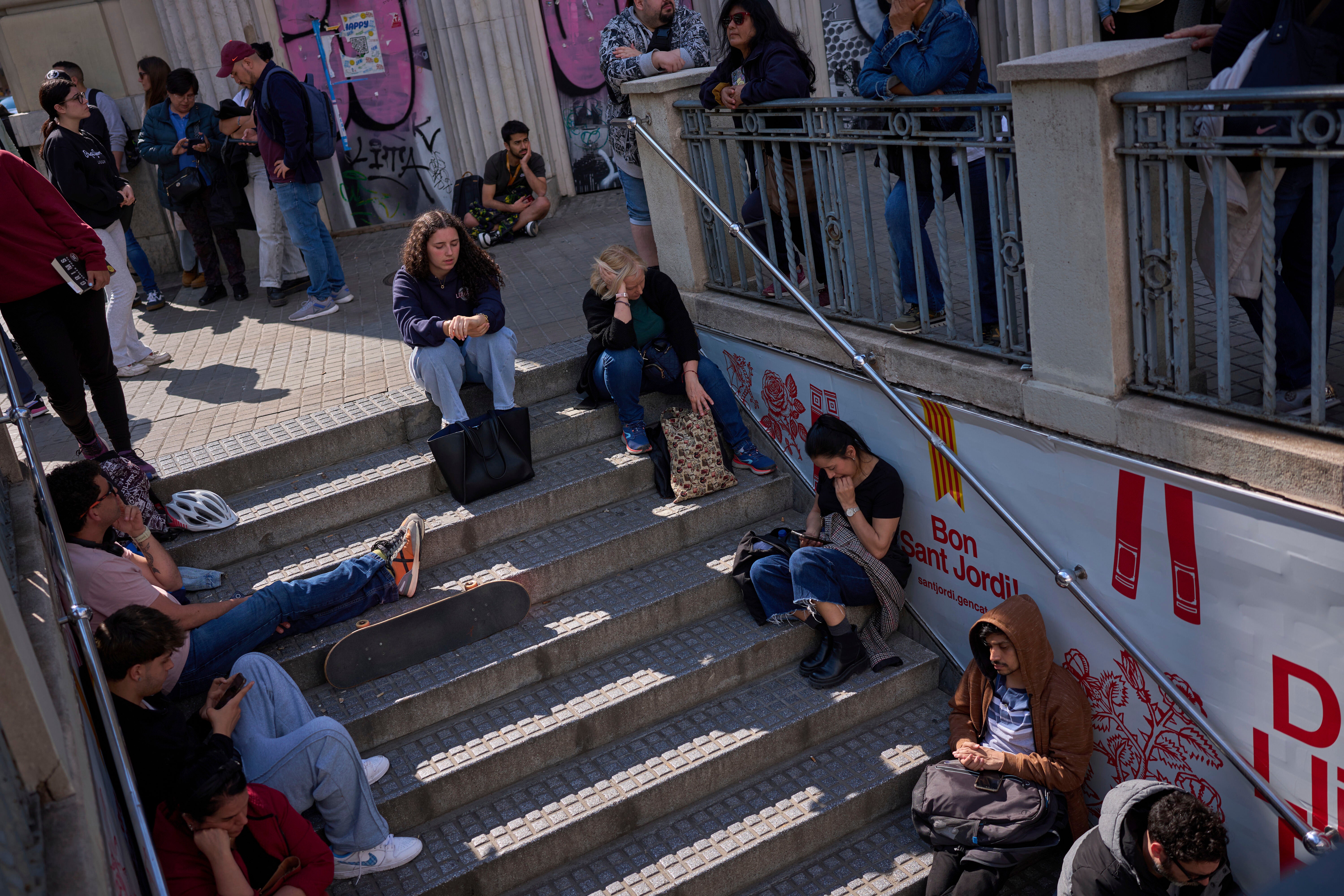 People wait outside a closed metro station, during the major power outage in Barcelona