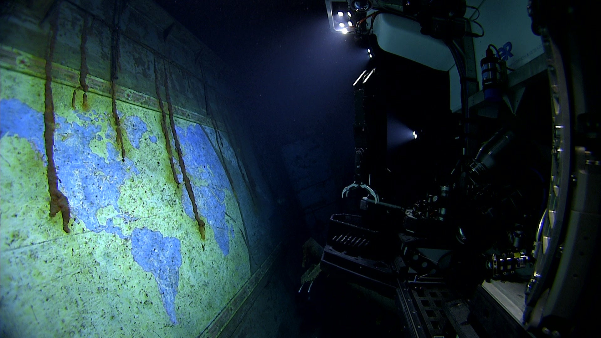 The lights of remotely operated vehicle Deep Discoverer illuminate the hand-painted mural, "A Chart of the Cruises of the USS Yorktown," during an expedition dive on April 19, 2025.