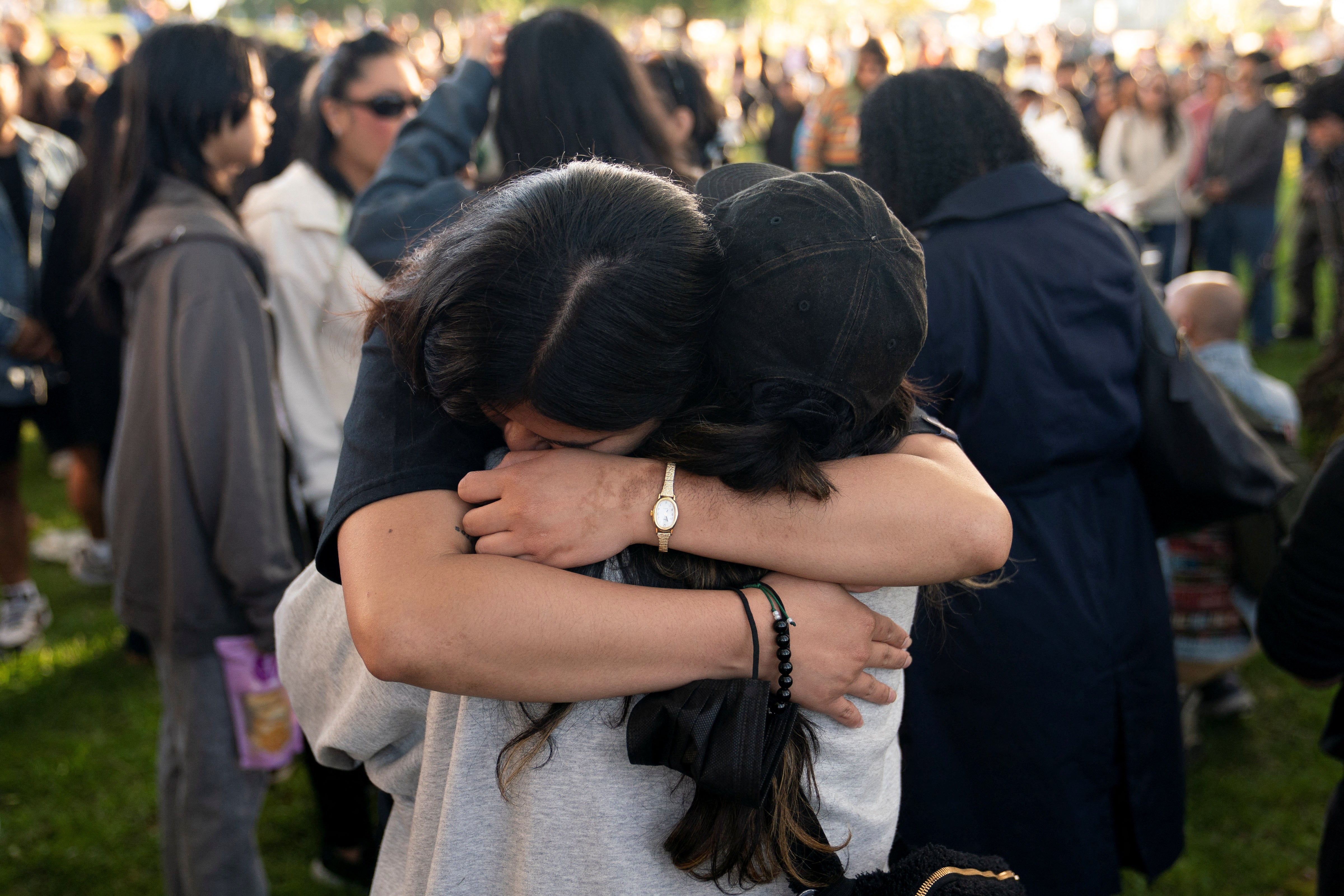 <p>Attendees embrace during a community gathering to mourn Lapu Lapu festival victims at Kensington Park</p>