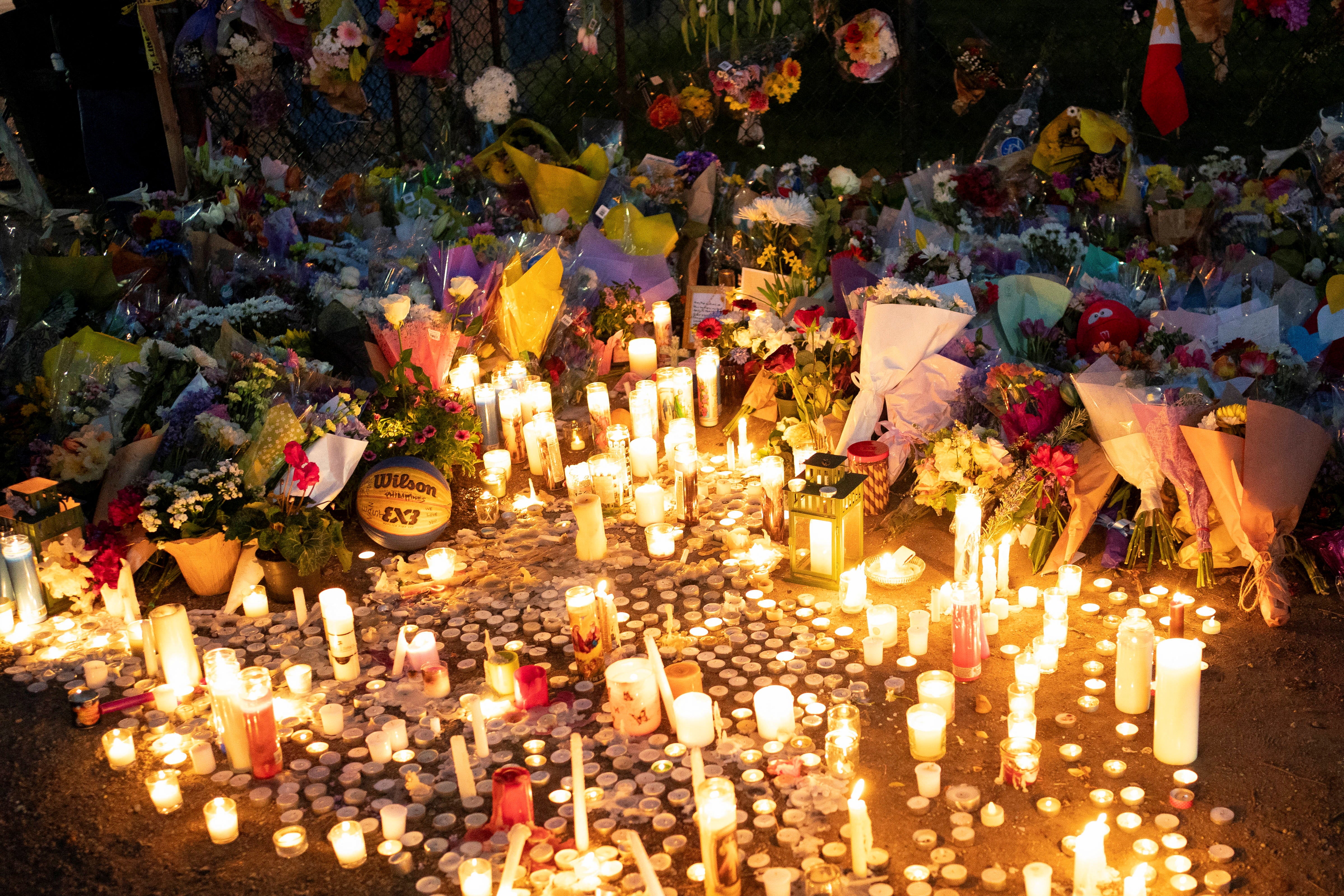Candles sit near flowers and other objects left by community members at the makeshift memorial