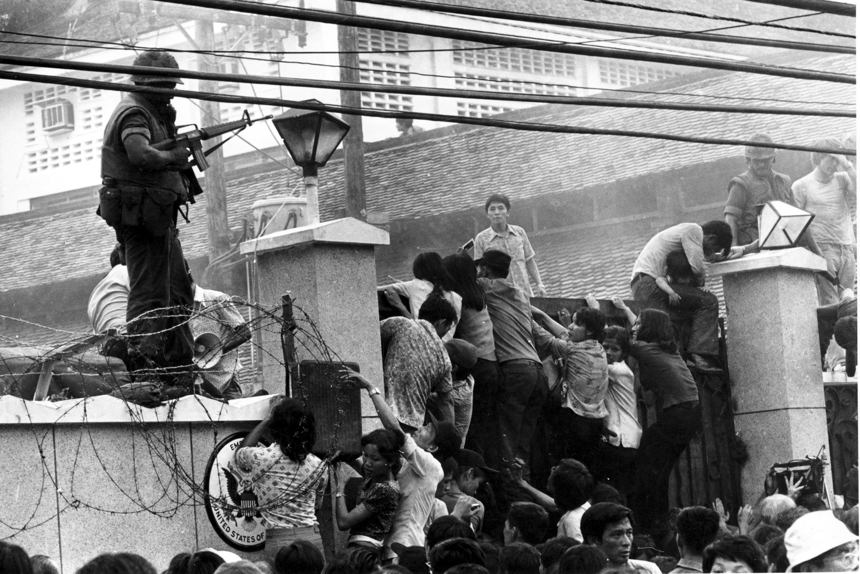 In this April 29, 1975 photo, Vietnamese people scale the wall of the US Embassy in Saigon, trying to get to the helicopter pickup zone, just before the end of the Vietnam War