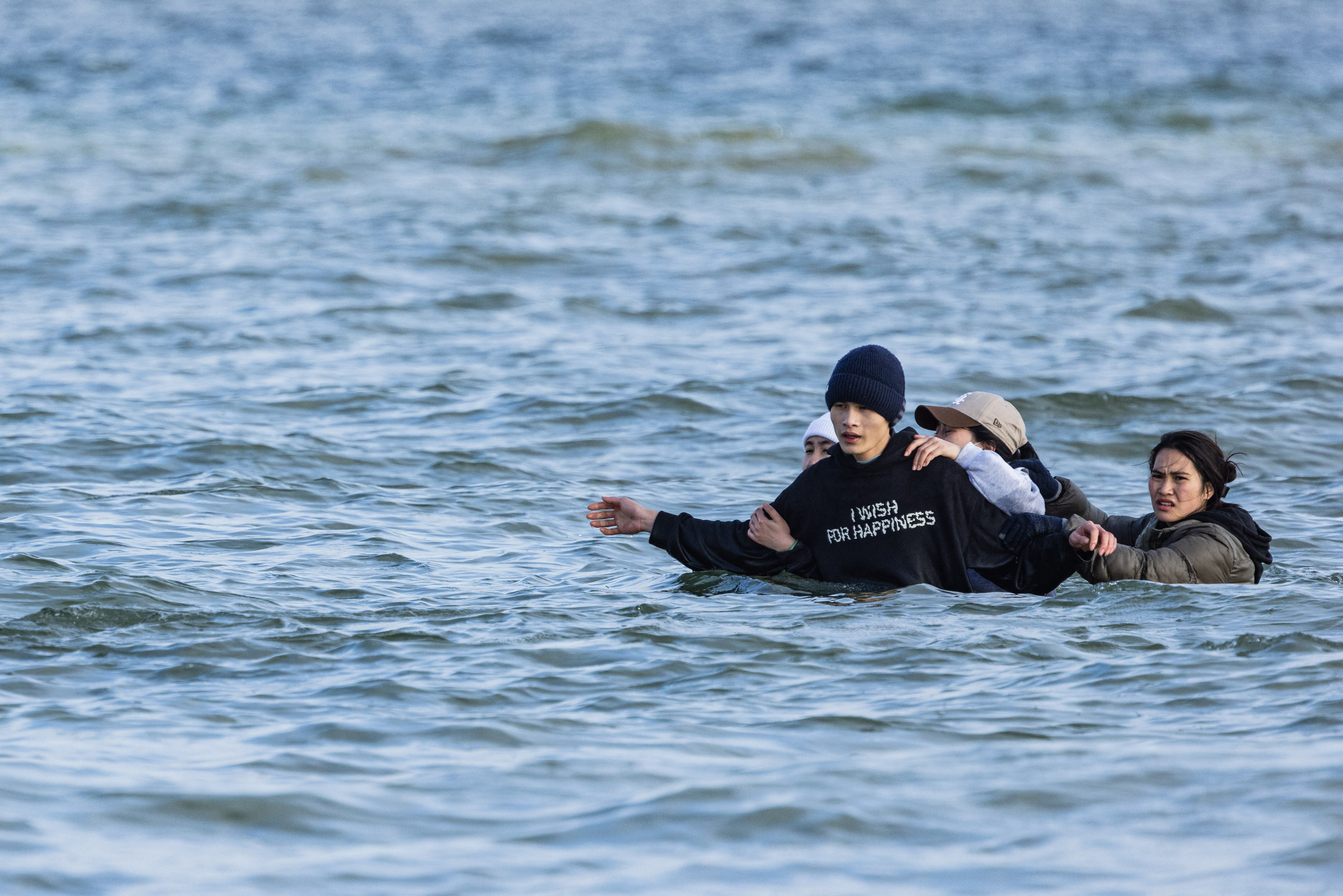 Migrants get into the water to board a smugglers’ boat off the beach of Gravelines, northern France, on 26 March