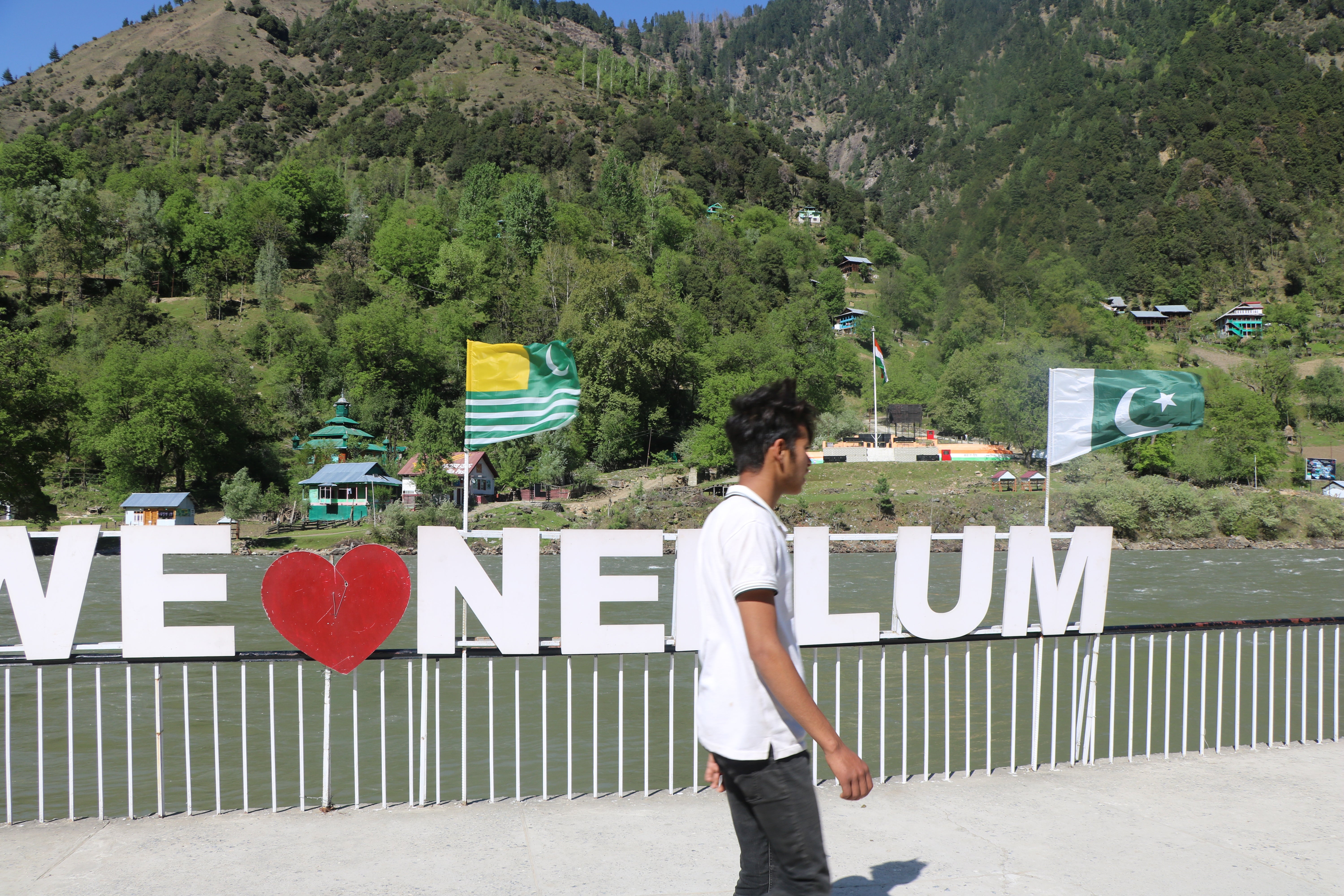 Pakistani (R) and Pakistani-administered territory of Azad Kashmir (L) flags are seen in Keran sector, in Neelum Valley, in the Pakistan-administered Kashmir