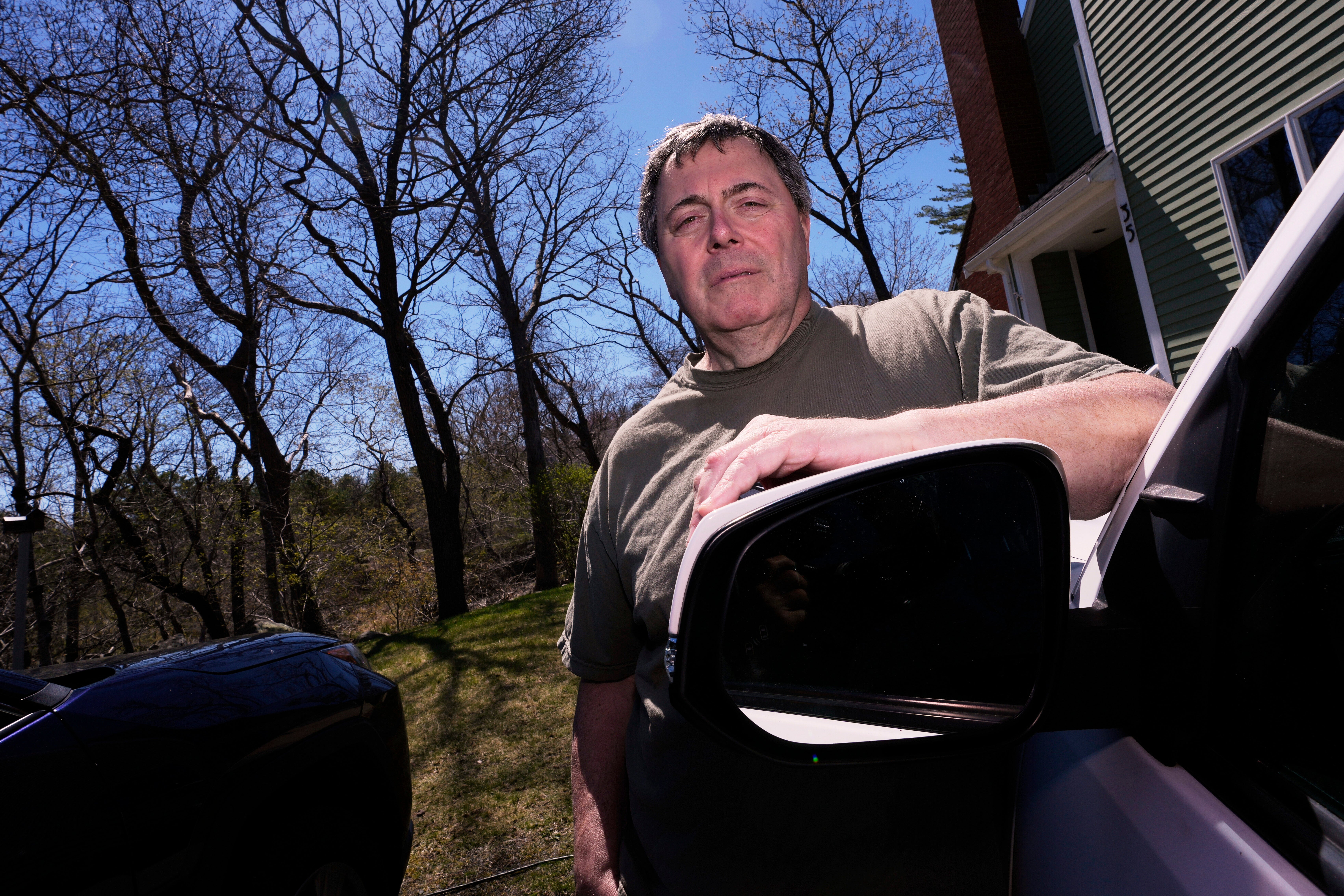 Ben Favaloro poses next to a replacement sideview mirror on his pick-up truck, after the original was broken by a rogue woodpecker earlier in the month