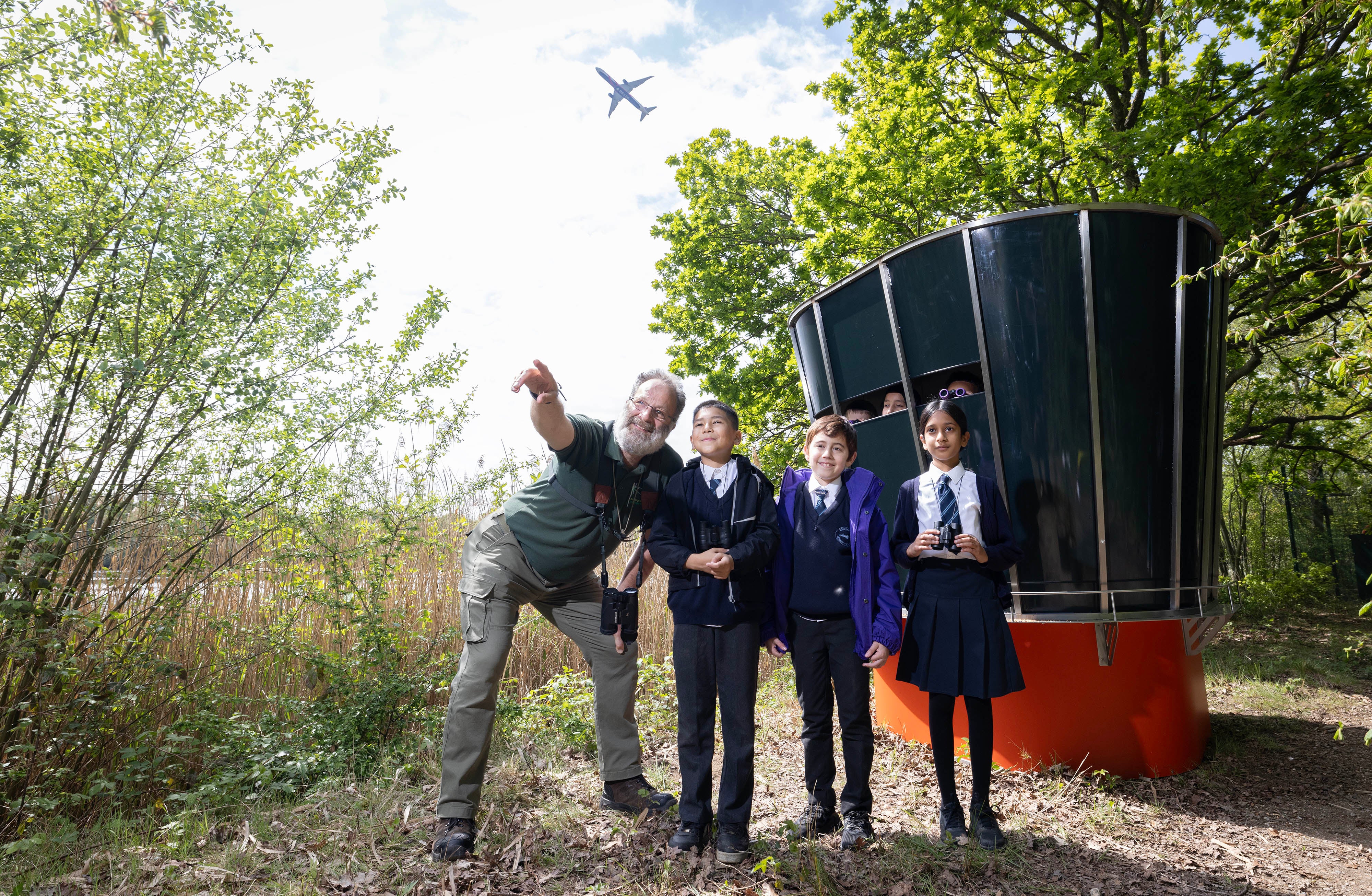 Biodiversity Manager at Heathrow Airport, Adam Cheeseman, and local school kids Subhan, Sarrah and Amin at a new Nature Traffic Control Tower, a birdwatching hideaway designed to resemble Heathrow's control tower