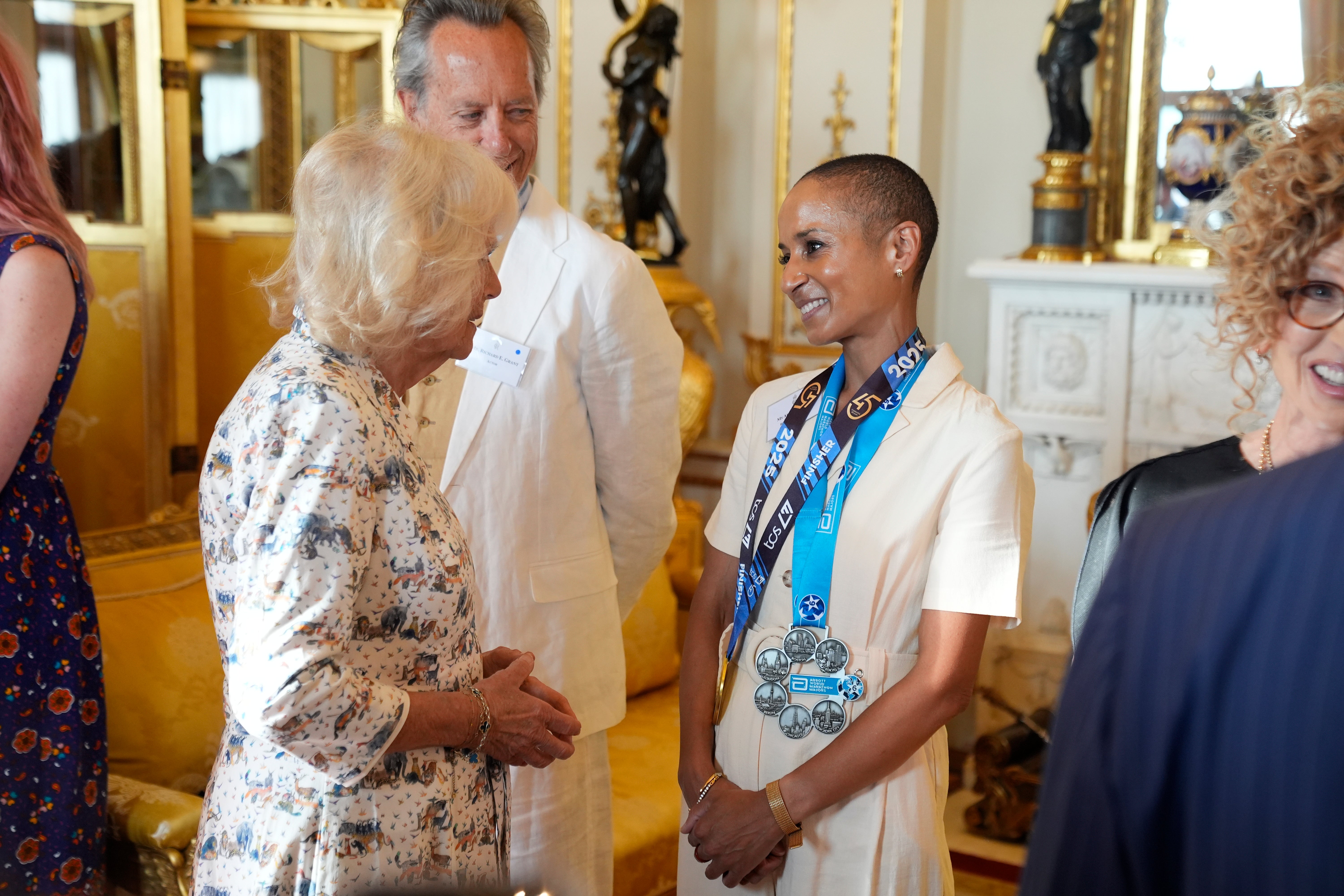 Queen Camilla speaks with broadcaster and presenter Adele Roberts, wearing her medals from the TCS London Marathon and Abbott World Marathon Majors