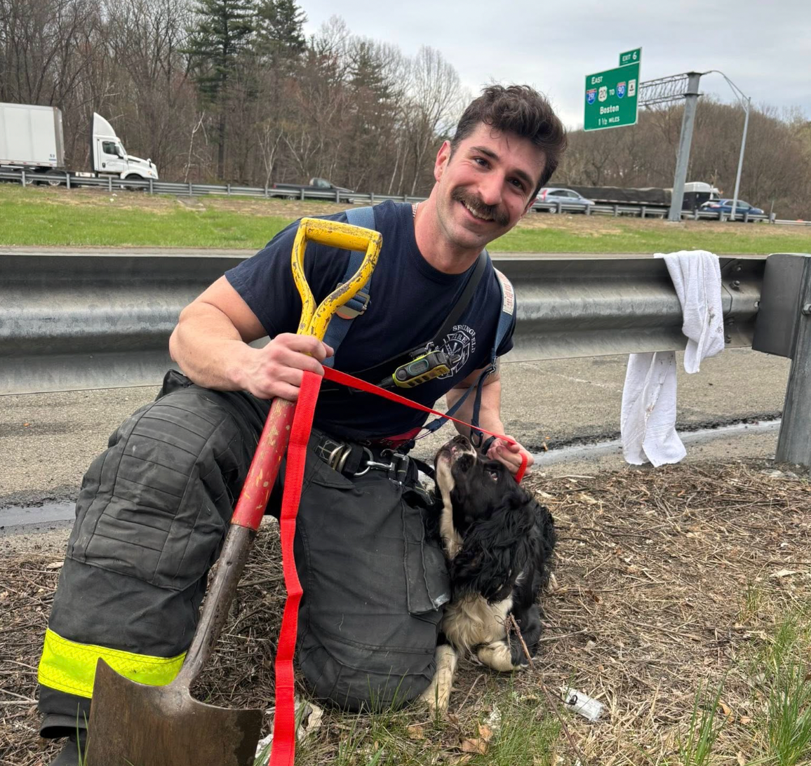 A firefighter poses with Ally, a dog missing for over a month, who was found down a storm drain during an unrelated incident. The animal has since been safely returned to her owners