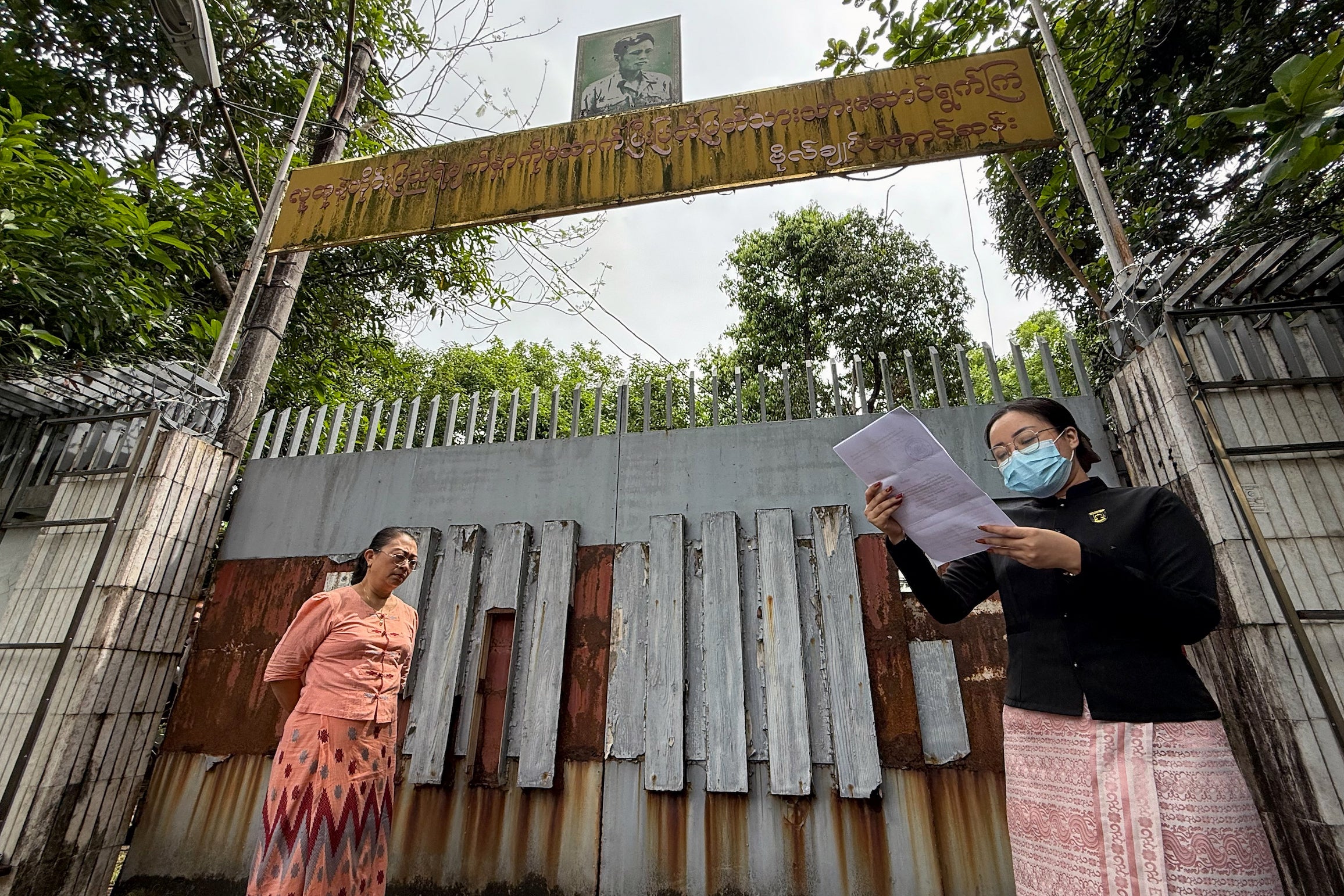An auction official reads a statement outside the gate of the family house of detained Myanmar civilian leader Aung San Suu Kyi in Yangon