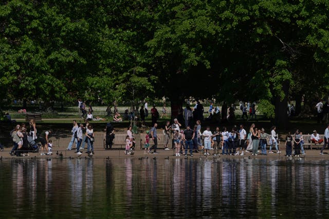 <p>People walk on a sunny day at a park in London during a warm spell</p>