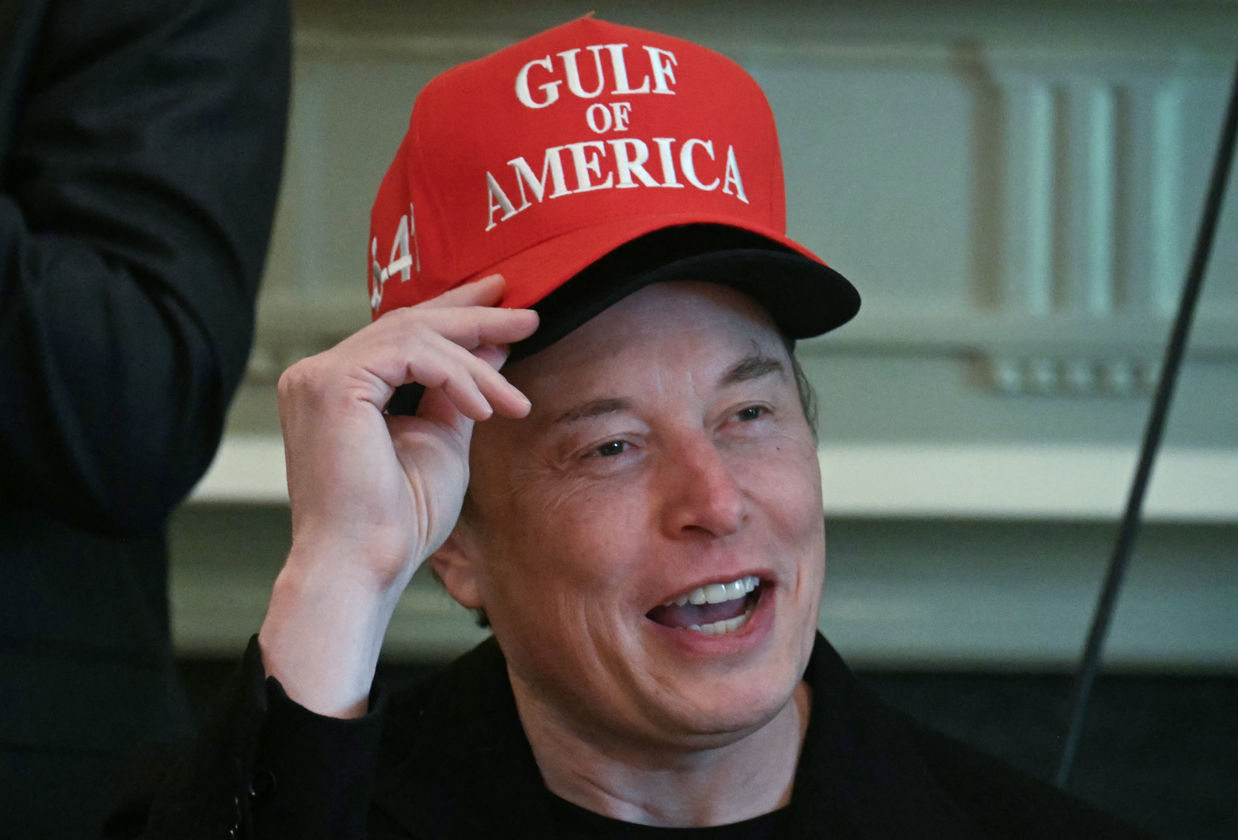Elon Musk, wearing two hats, speaks during a cabinet meeting in the Cabinet Room of the White House last Wednesday