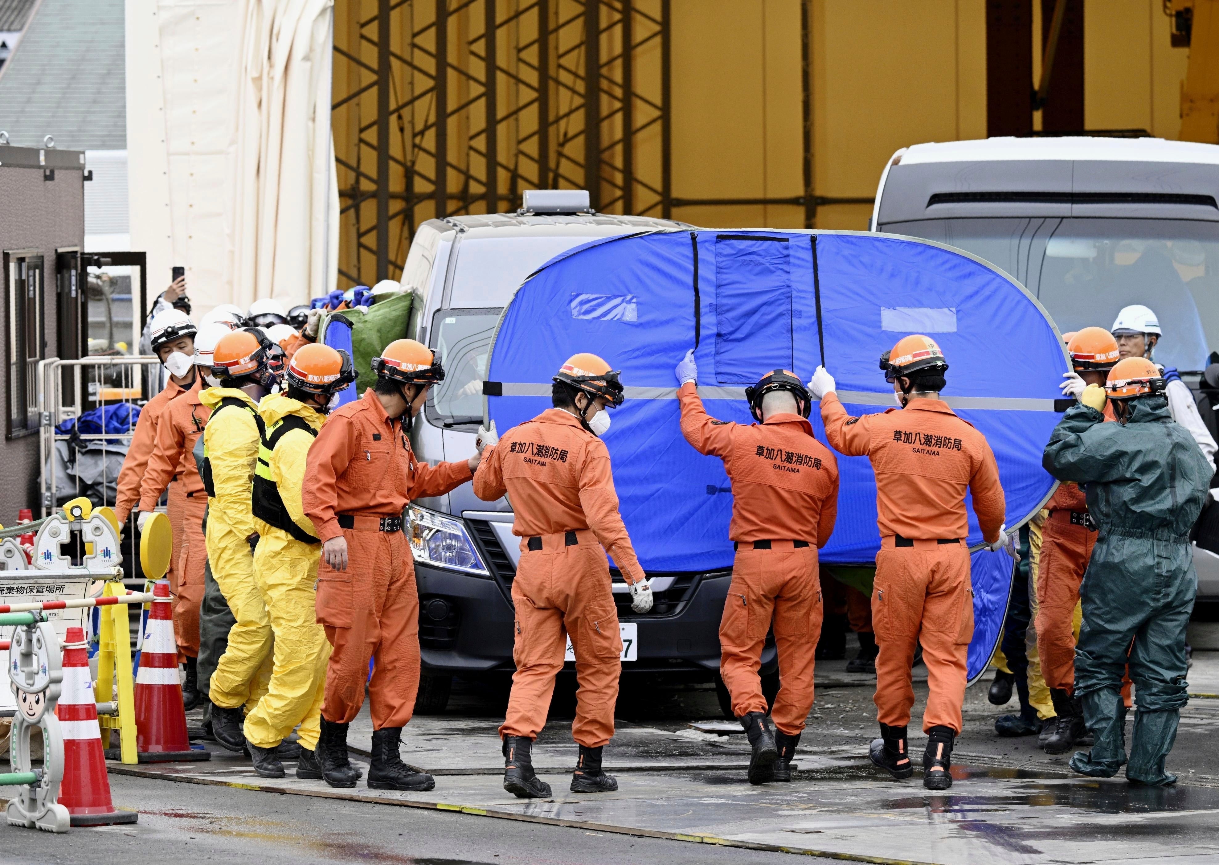 A vehicle carrying a body, believed to be that of the driver found during a search inside the sewer pipe, leaves the scene of the road collapse accident on a street, Friday May 2, 2025 in in Yashio, northeast of Tokyo. (Kyodo News via AP)