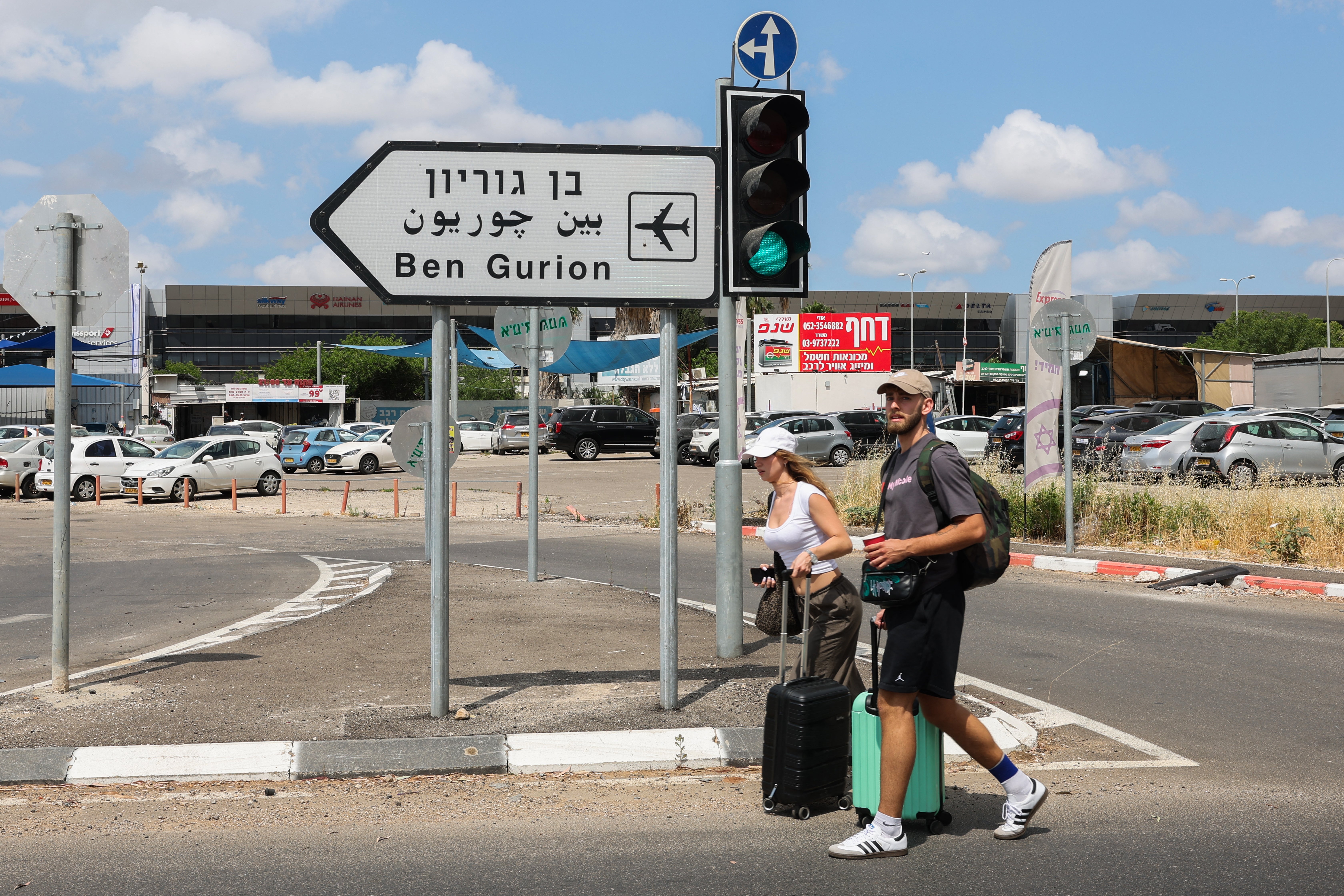 Travelers pull their luggage as they walk towards Ben Gurion airport after main road entrances to the facility were closed by Israeli police