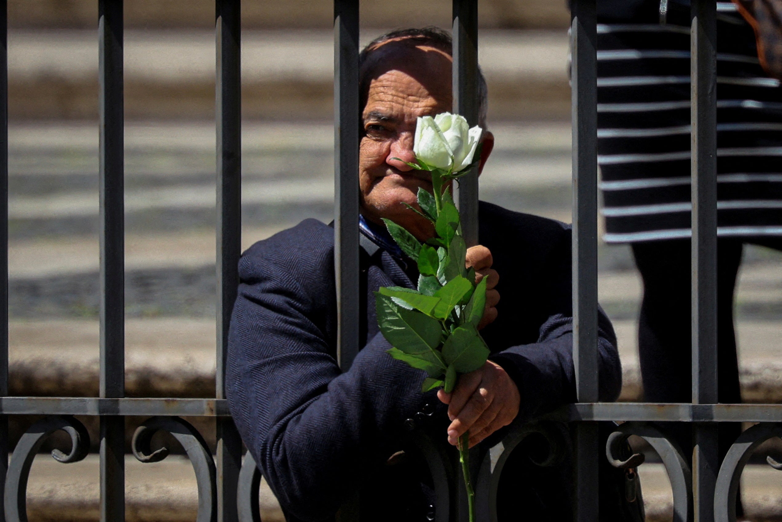 Antonino Siracusa, part of a group of homeless and poor chosen to bid a final farewell to Pope Francis, holds a white rose as he stands behind a fence at the Basilica of Saint Mary Major, where the pontiff is buried, in Rome, Italy, April 26, 2025