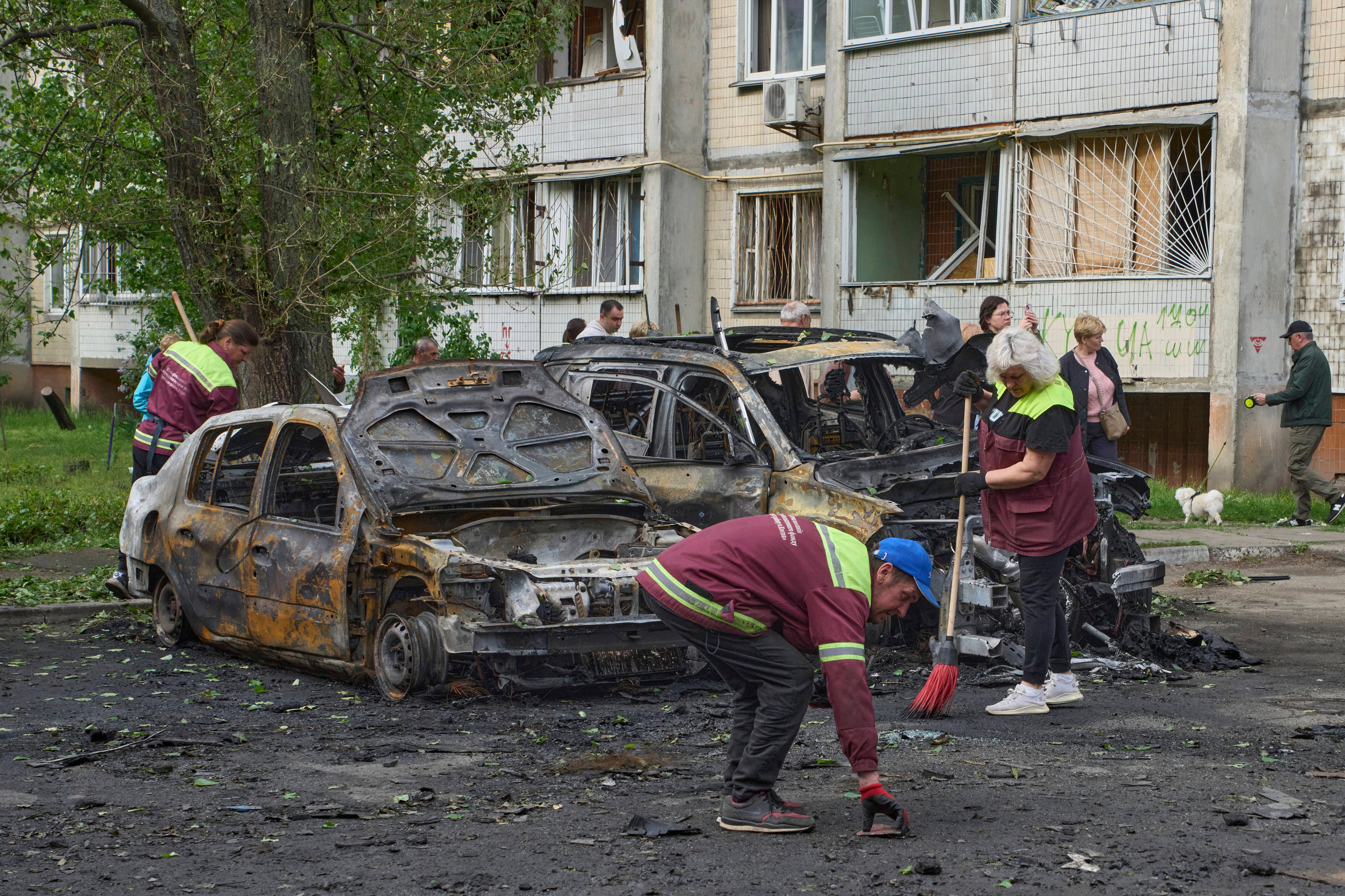 Municipal workers clean up around burnt cars in the residential area following Russia's drone attack in Kyiv, Ukraine, Sunday, May 4, 2025. (AP Photo/Efrem Lukatsky)