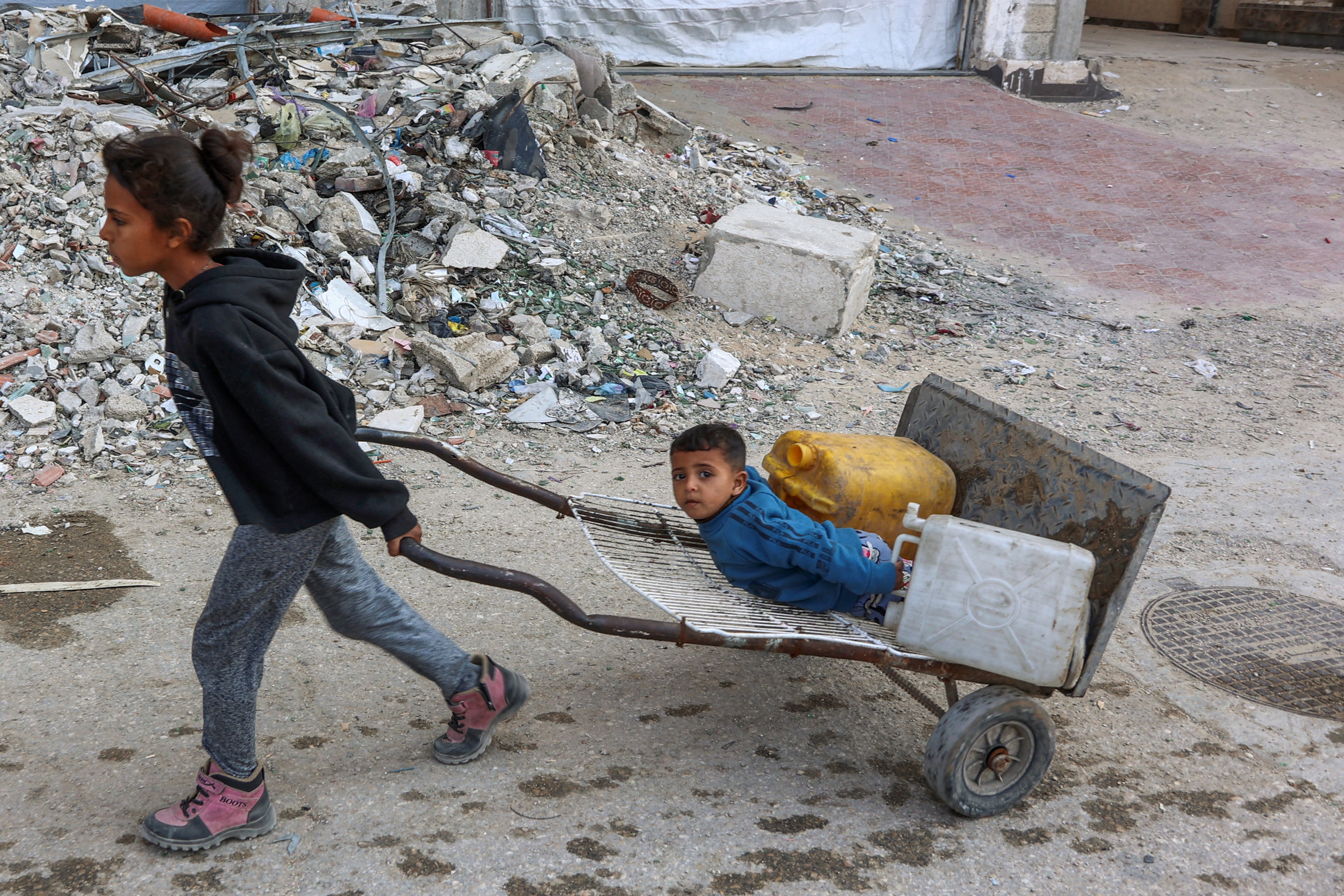 Palestinian children head to a water distribution point to fill their containers in Gaza City