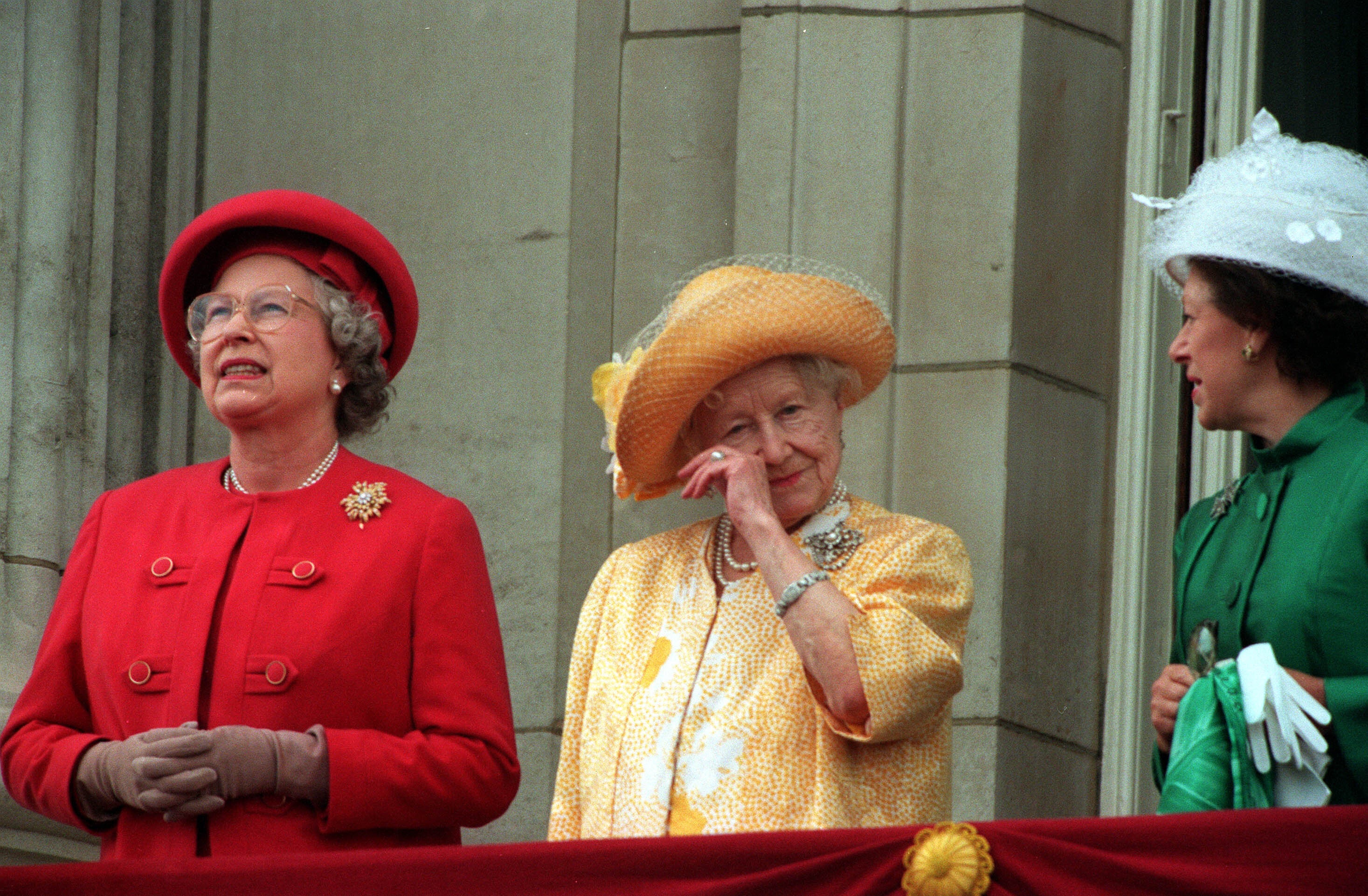 The Queen Mother wipes her eye as she stands on the Buckingham Palace balcony during the 50th anniversary of VE Day with the late Queen Elizabeth II and Princess Margaret