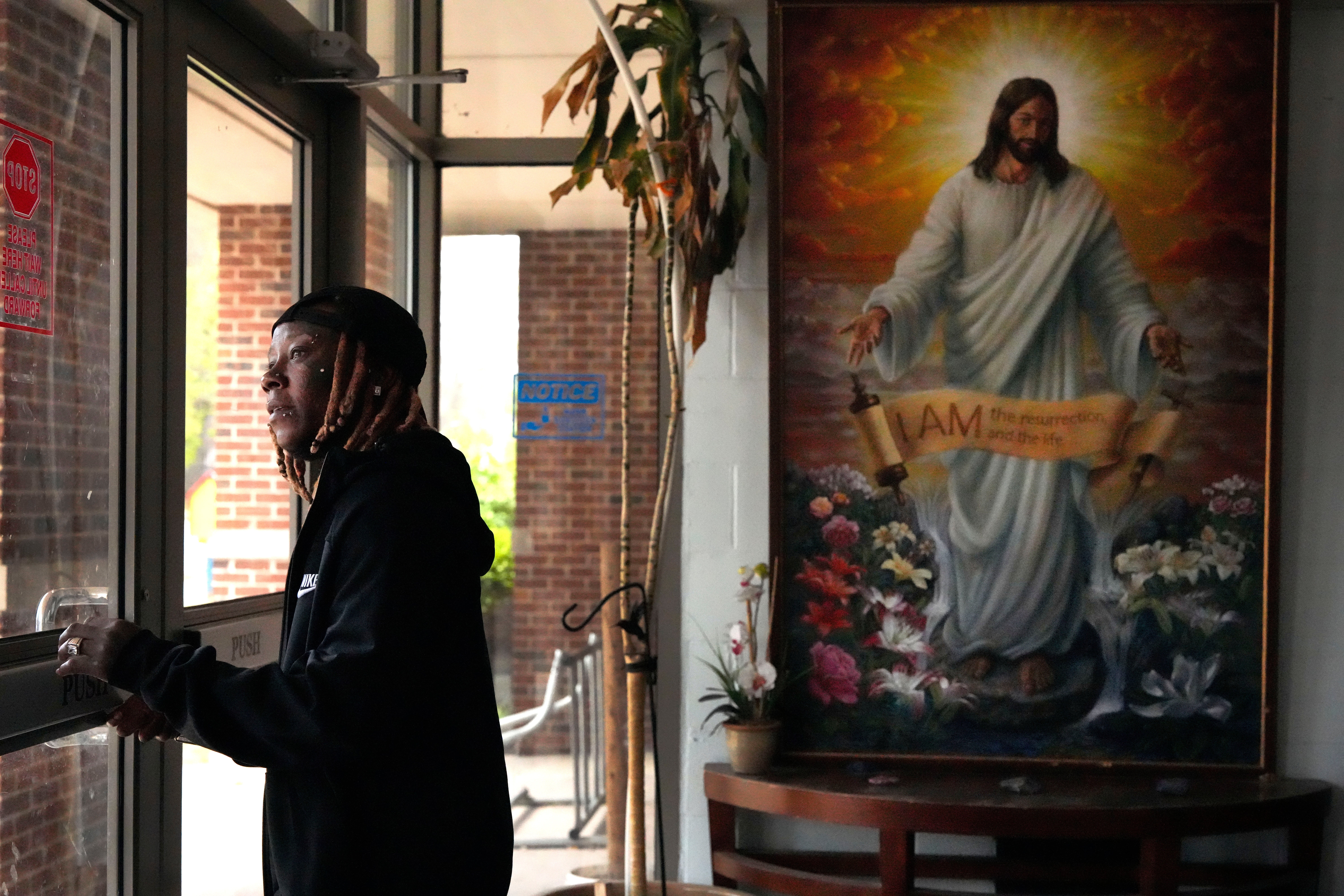 Tazz Webster, who ultimately wound up homeless after an apartment manager allegedly ridiculed and shoved him because he is transgender, exits through the front door of a community center, April 9, 2025, in St. Louis. (AP Photo/Jeff Roberson)
