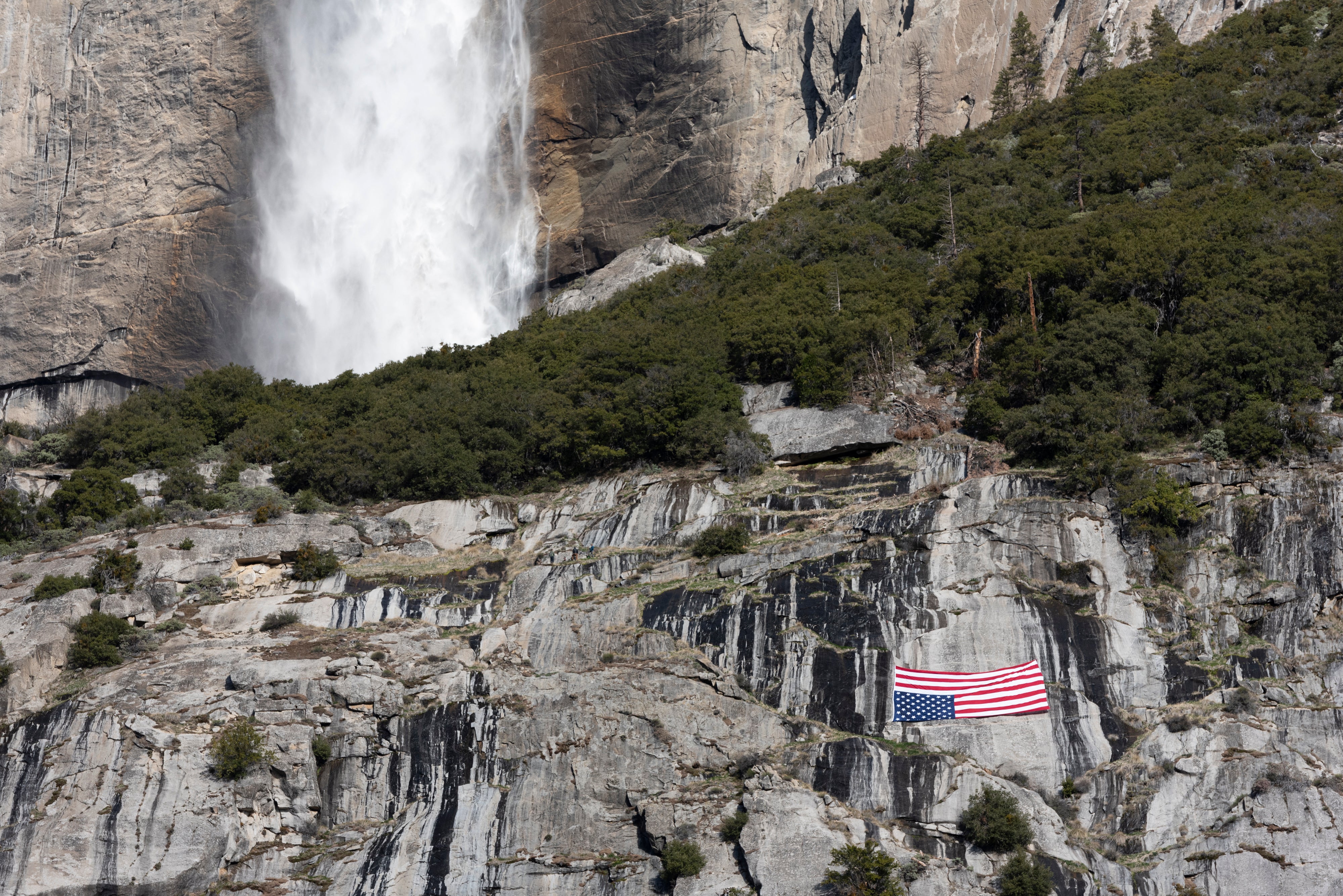 An American flag is hung upside down below the Upper Yosemite Falls during a protest against federal employee layoffs at California’s Yosemite National Park earlier this year. Conservation group leaders fear more layoffs are coming