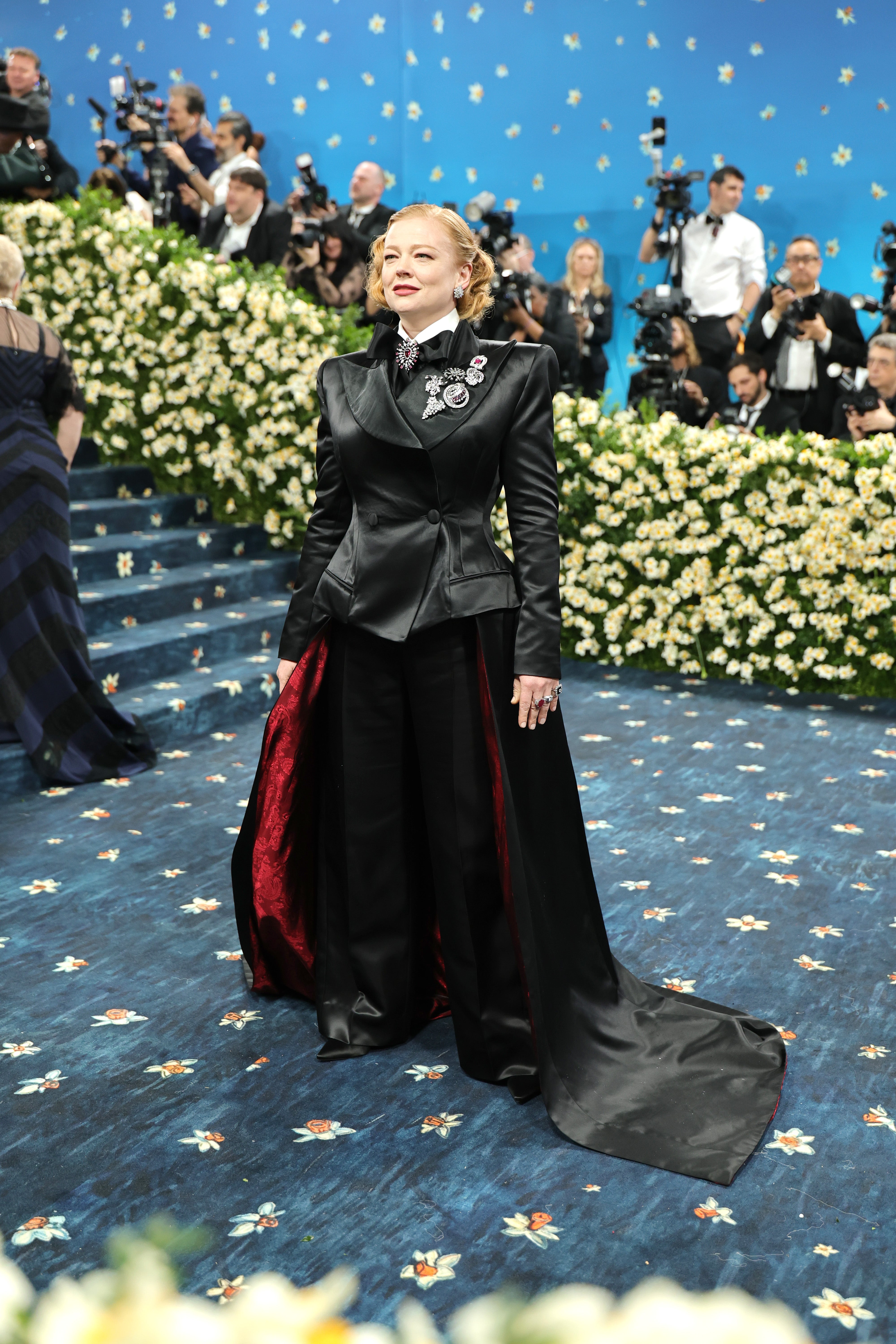 Sarah Snook wore a satin black jacket with a matching bowtie. Her jacket, adorned with silver brooches, also includes a floor-length train that was red on the inside