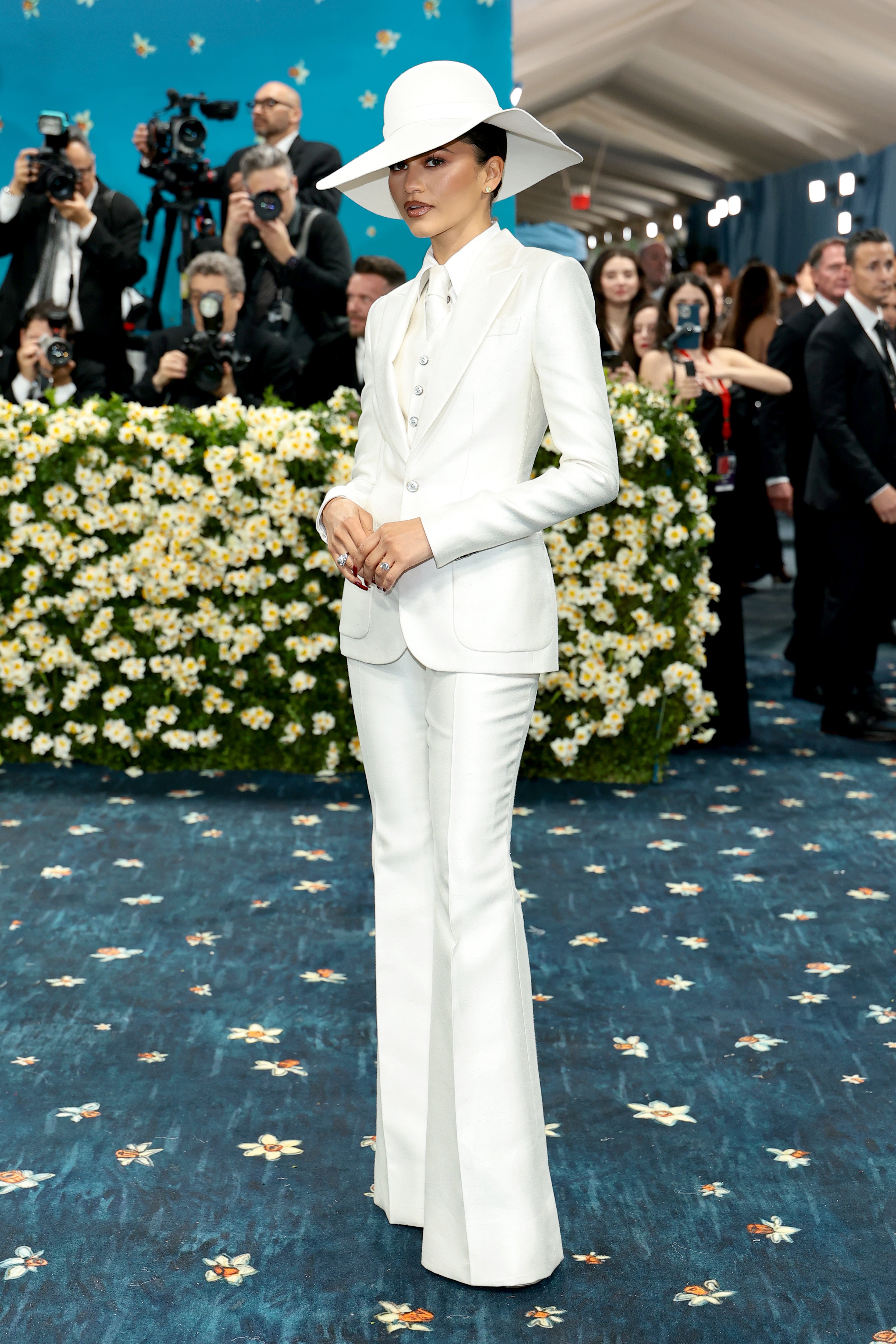 Zendaya wore an all-white tuxedo, featuring a matching tie and hat. She also completed the look with silver rings and earrings