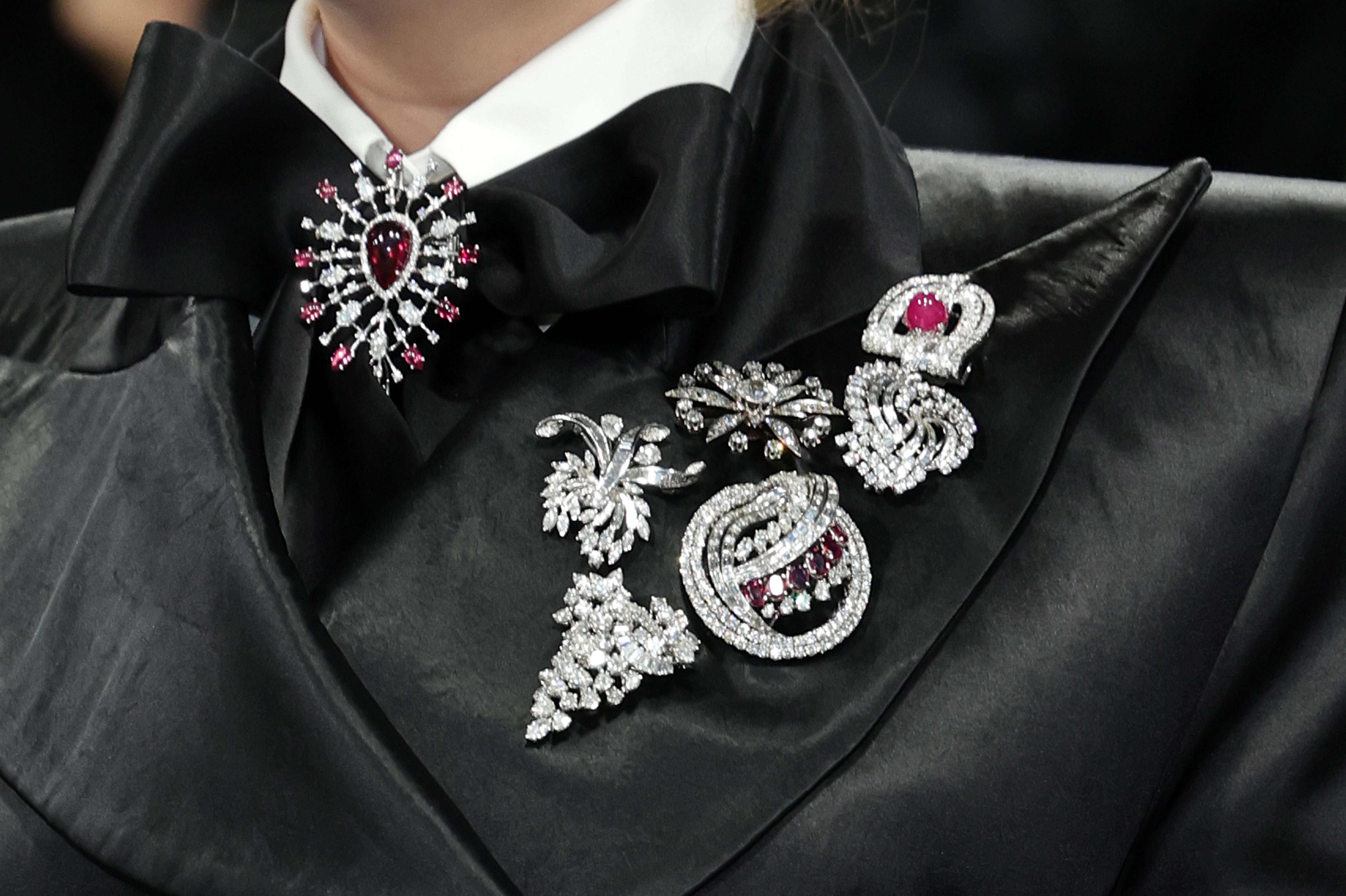Snook had a series of silver brooches on the side of her jacket. She also had a silver and red brooch attached to the middle of the tie of her outfit