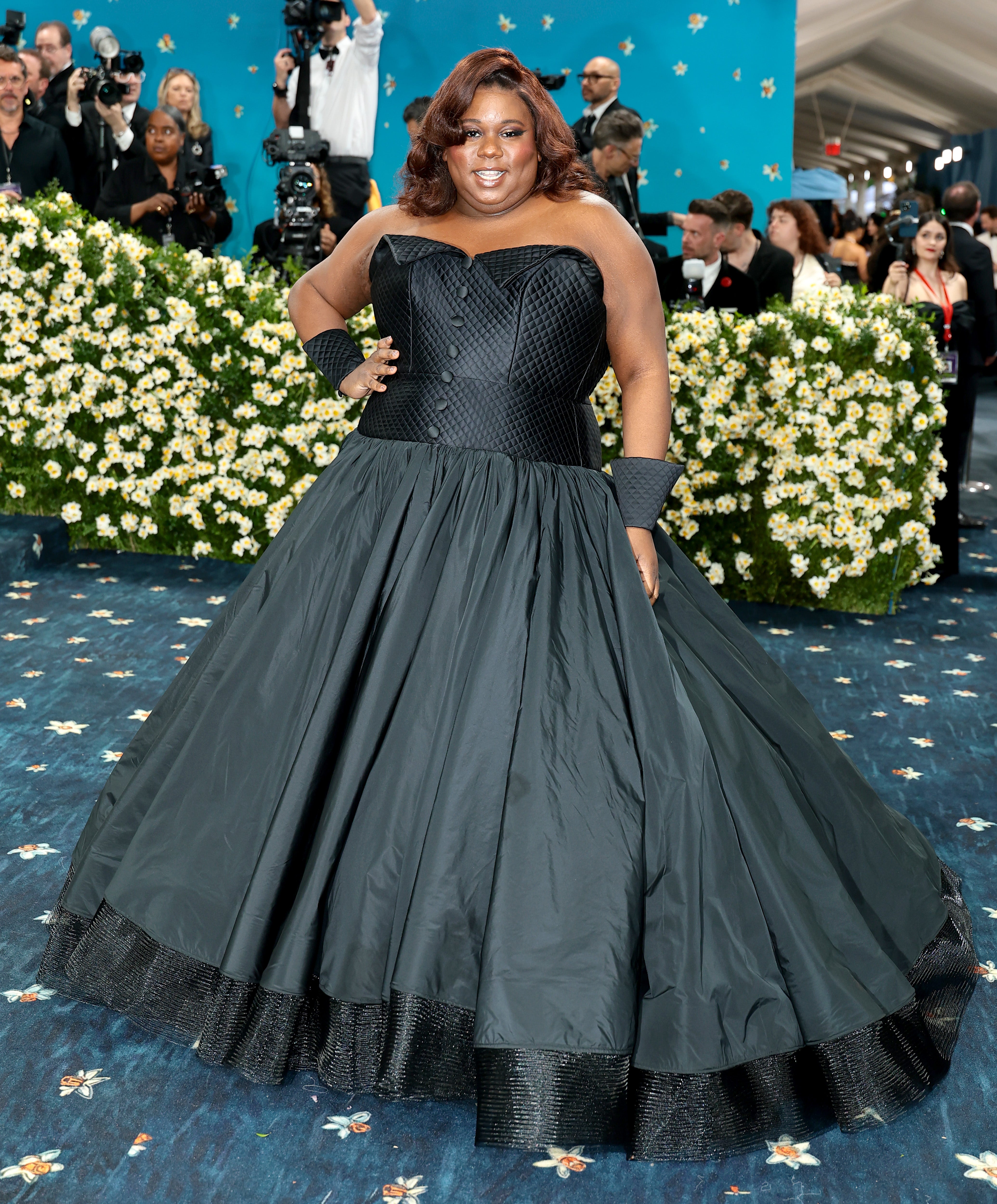 Tony winner Alex Newell wore a black gown with a pleated skirt and buttons on the top. They also wore black bracelets made from the fabric of their dress