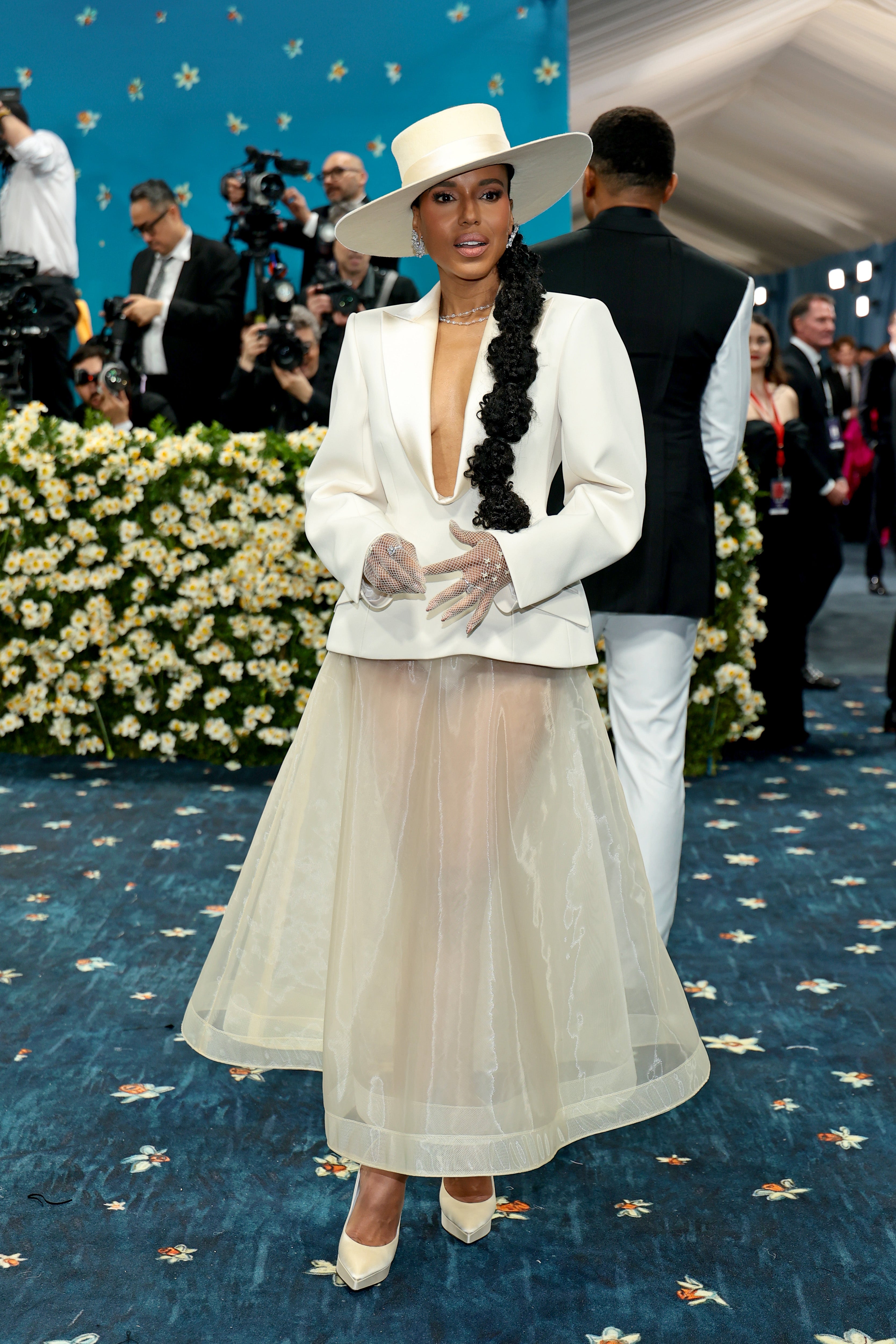 Kerry Washington wore a white, unbuttoned jacket, paired with a matching sheer skirt. She also wore a beige top hat, white heels, a sheer skirt, and fishnet gloves