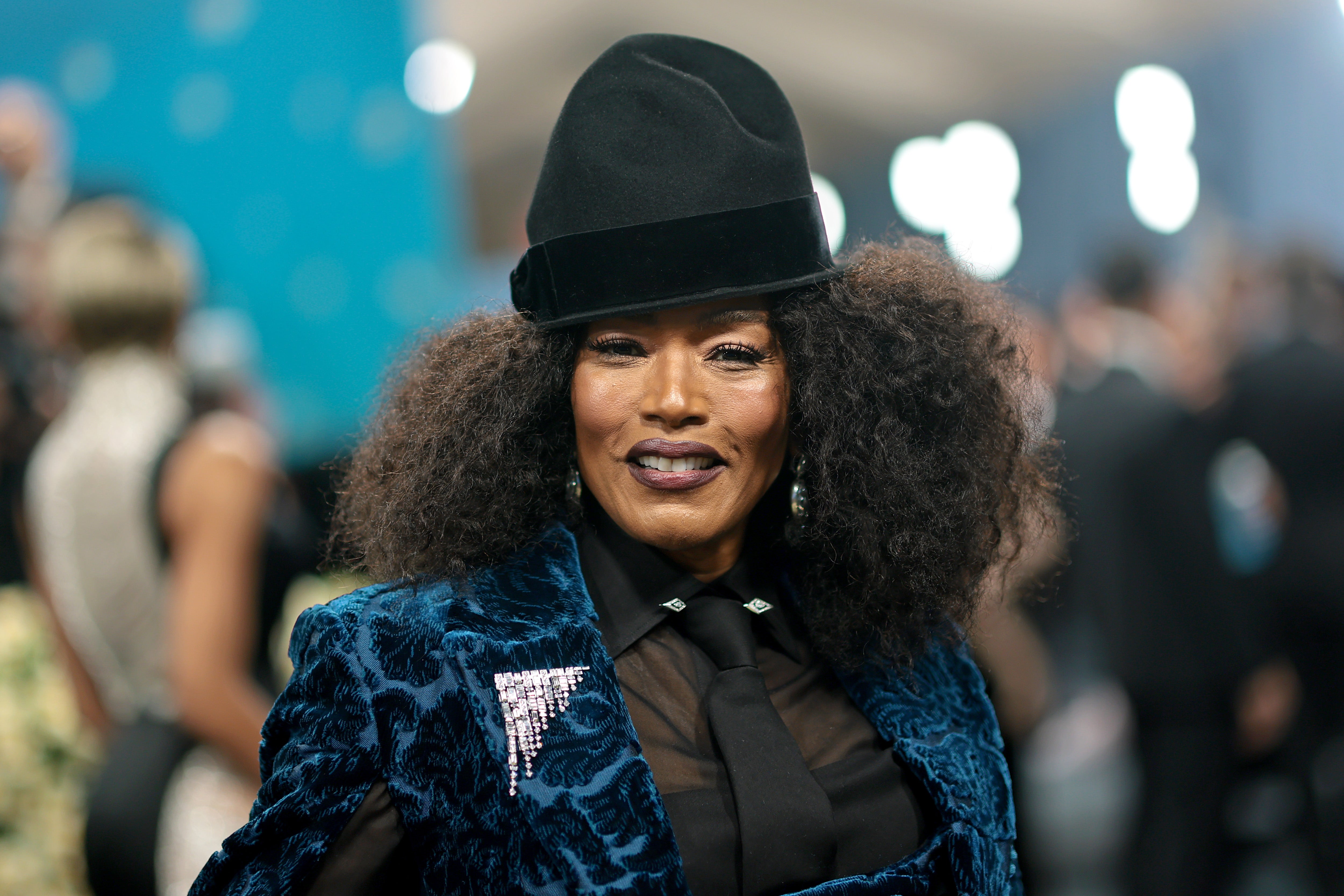 Angela Bassett arrived in a blue velvet pantsuit, sheer long-sleeved top, and a matching black tie. She also wore a black top hat and had a diamond pin on her jacket