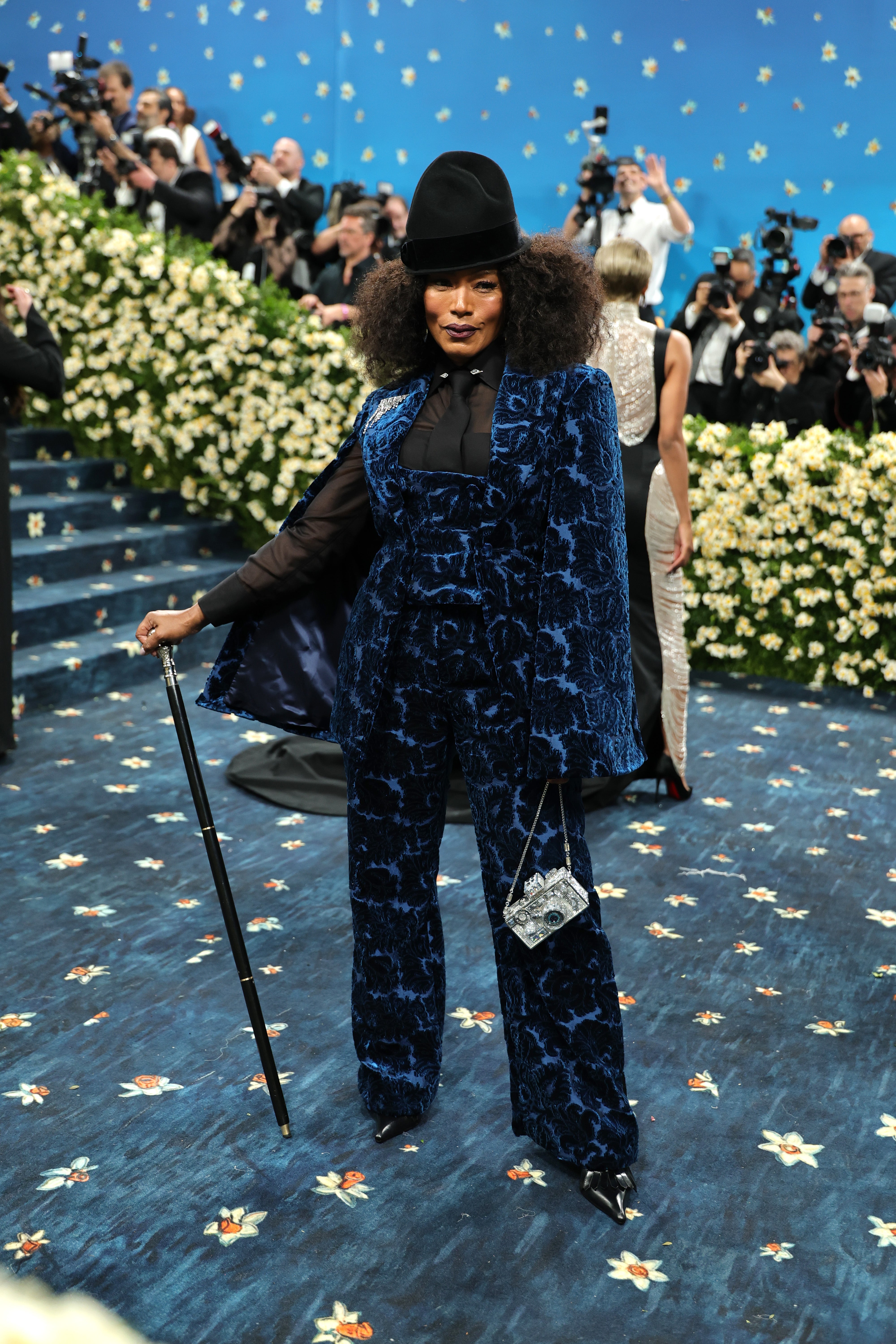 The actor completed her look with a black cane in hand and a silver square purse, which looked like a camera