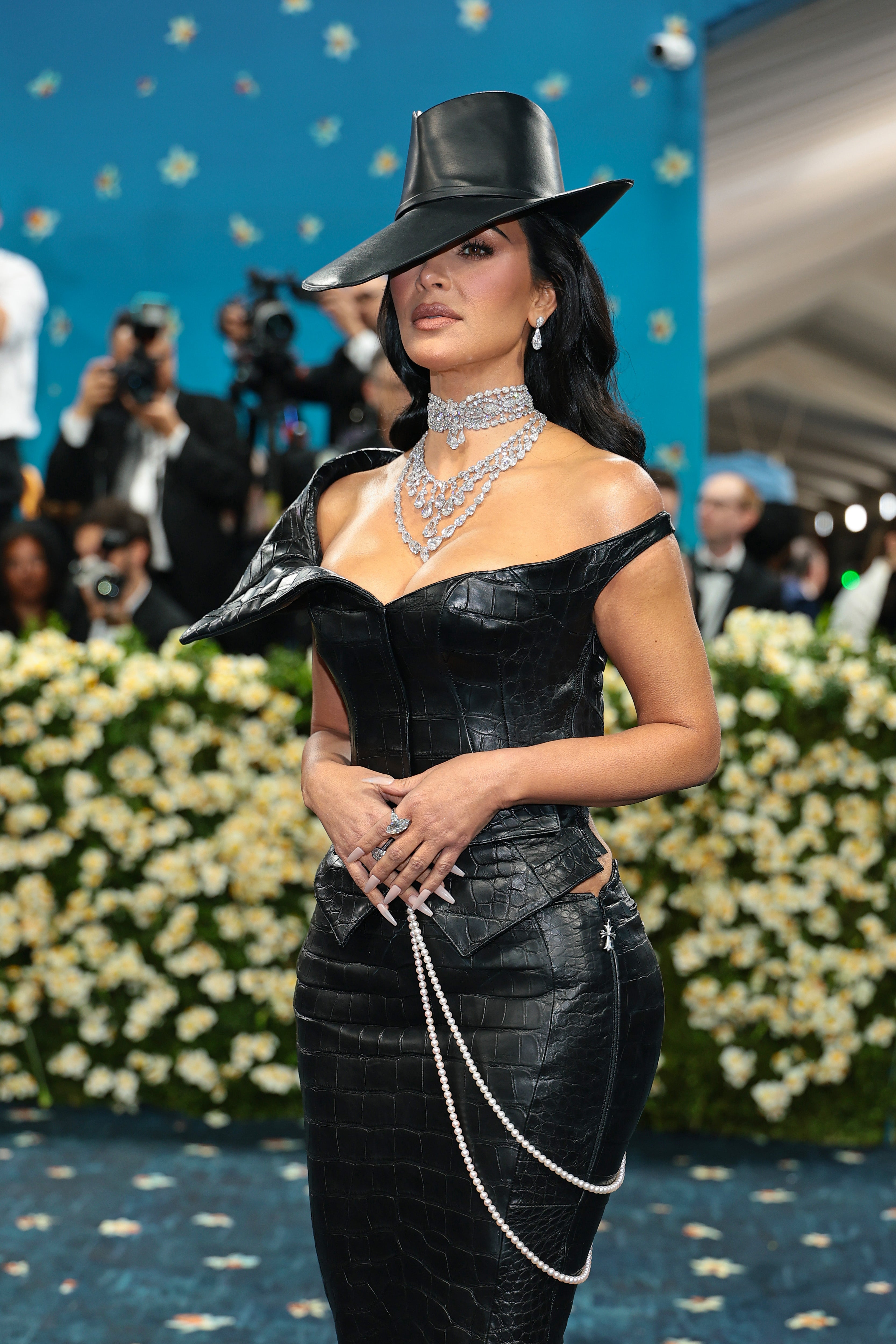 Kim Kardashian wore a black, leather off-the-shoulder corset top and a matching skirt. She opted for a matching hat, which covered one of her eyes, and diamond necklaces