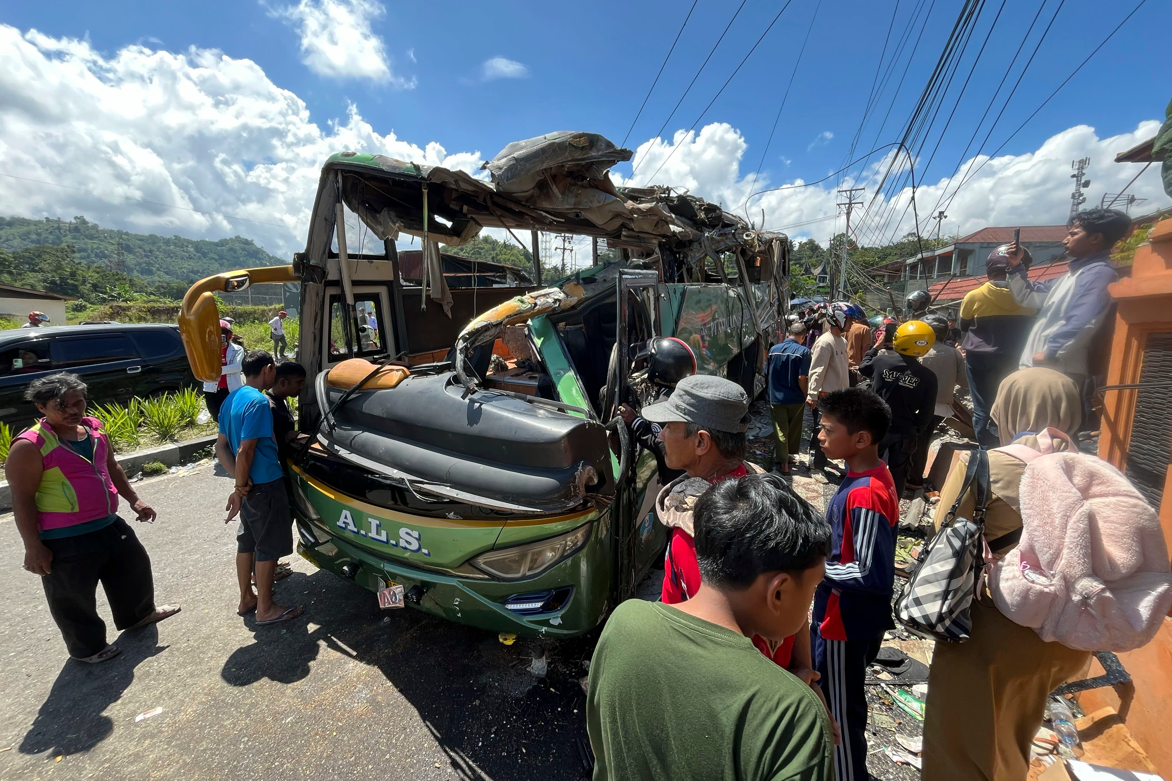 People inspect the wreckage of a bus after it sped out of control on a downhill road and overturned in Padang Panjang, West Sumatra