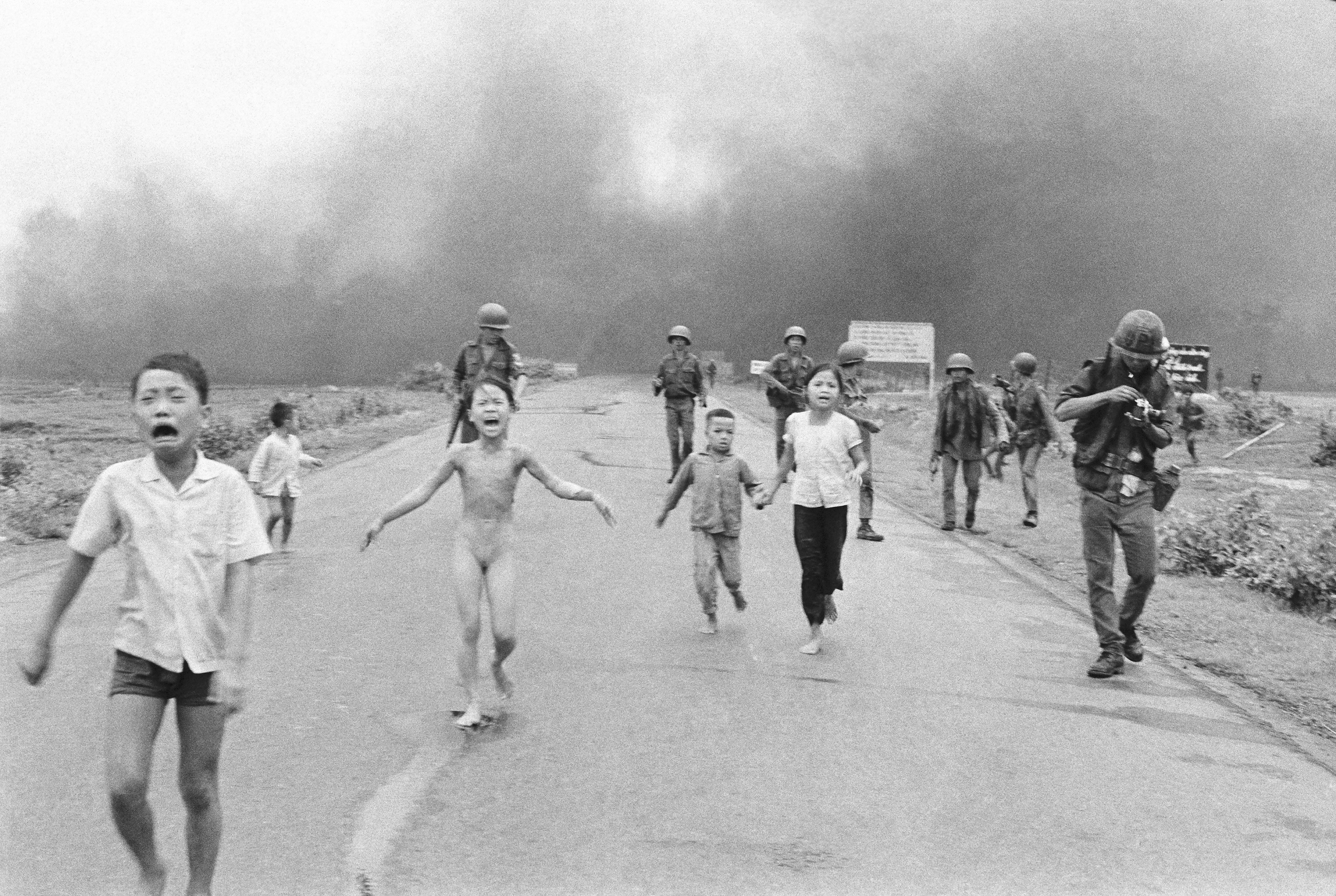 South Vietnamese forces follow after terrified children, including 9-year-old Kim Phuc, center, as they run down Route 1 near Trang Bang after an aerial napalm attack on suspected Viet Cong hiding places, June 8, 1972
