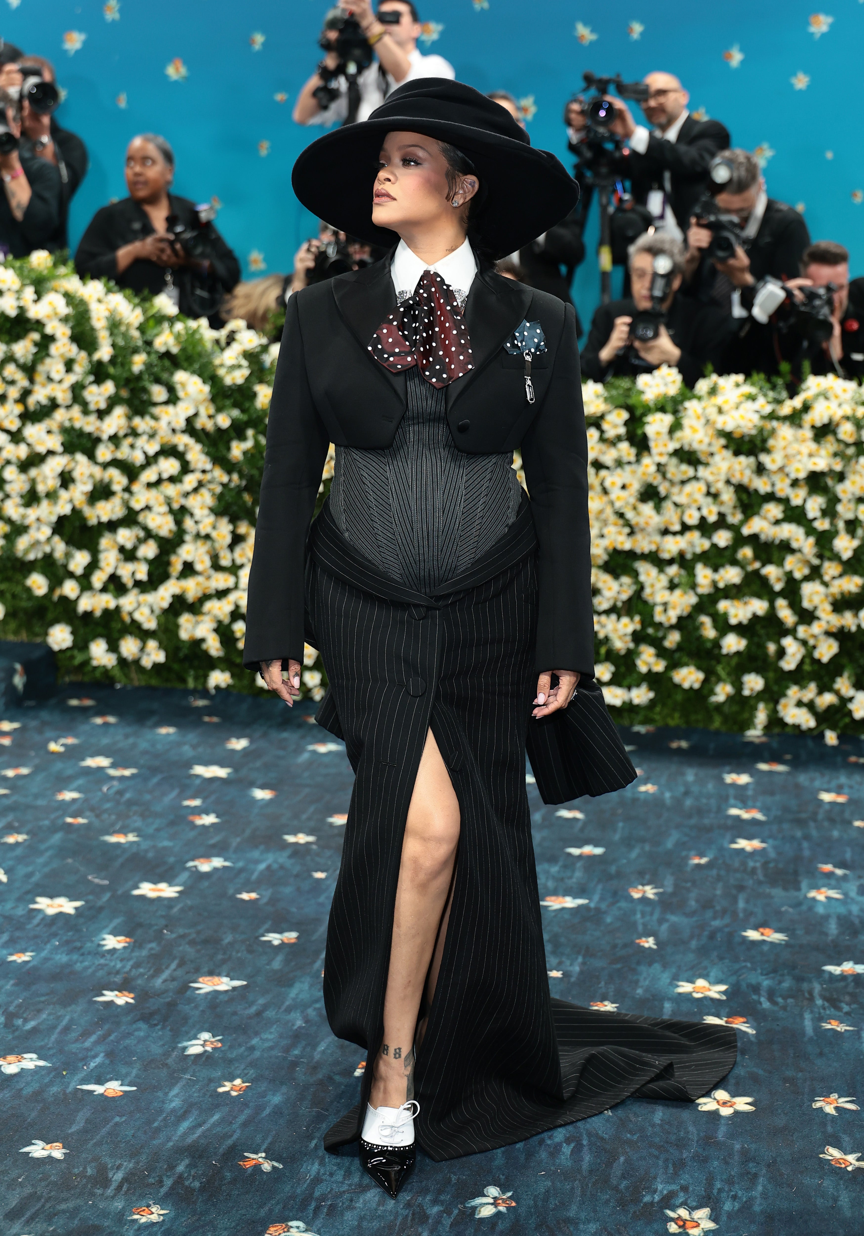 Just like in 2023, Rihanna was the last star to arrive on the Met Gala red carpet hours after live coverage ended. She posed in a Marc Jacobs look, featuring a gray bodysuit, cropped black blazer, and pinstripe black skirt. She accessorized with a red and white polka dot bowtie