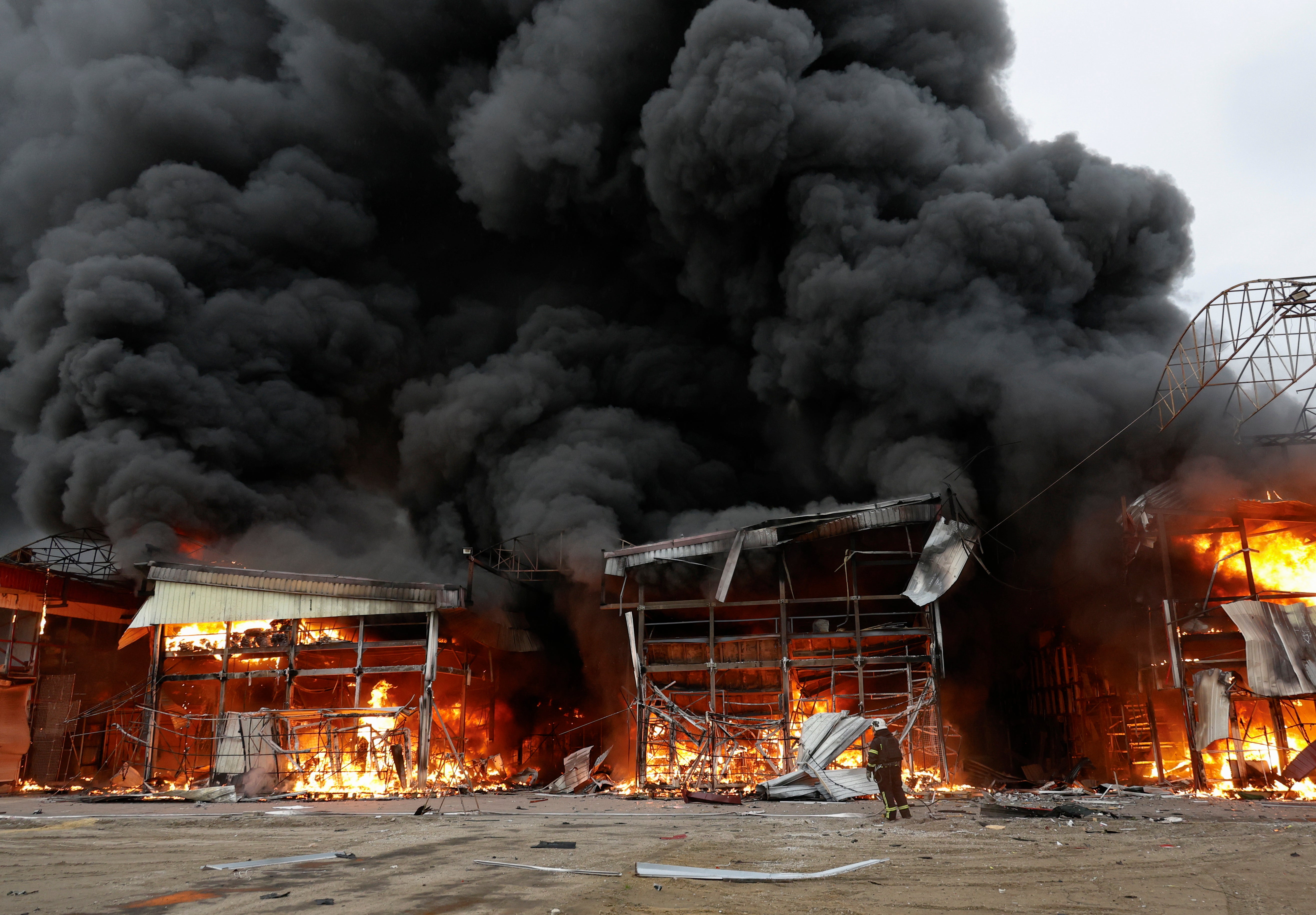 Emergency services battle a blaze at the site of a drone strike on the Barabashovo market in Kharkiv
