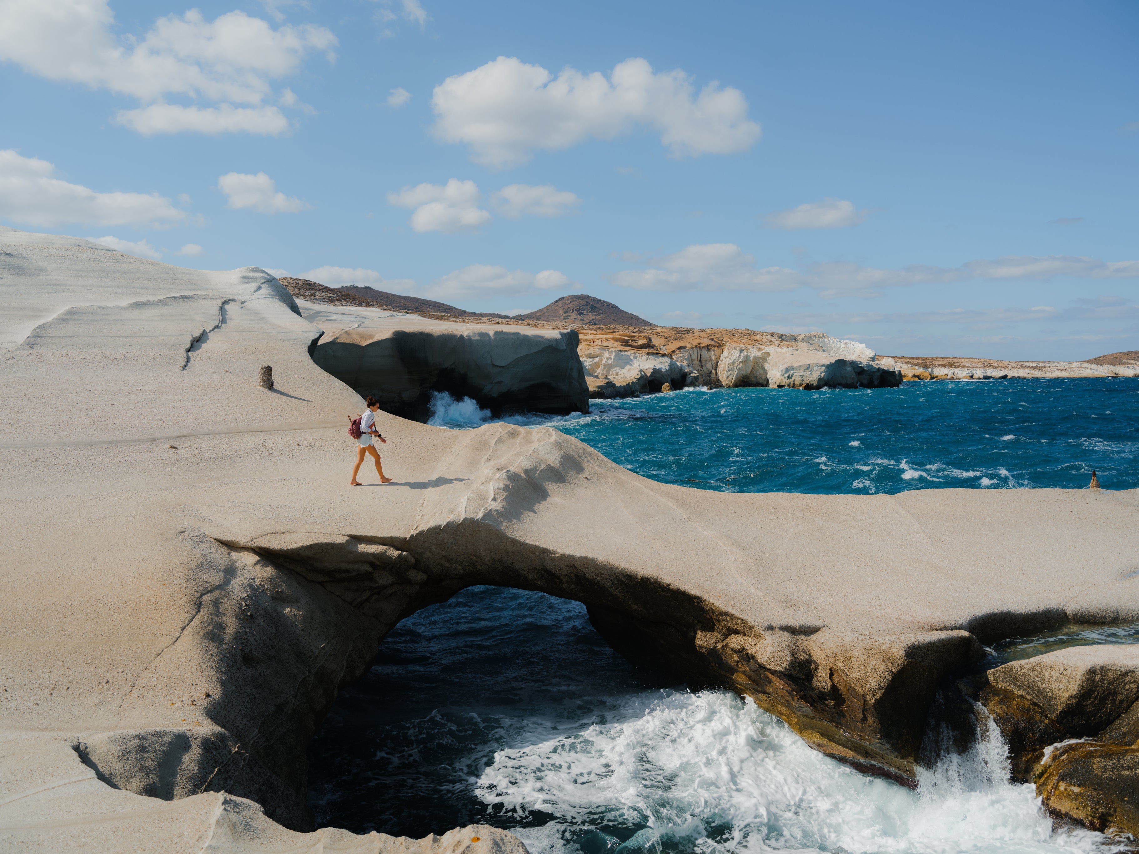 A woman explores the white cliffs of Sarakiniko beach in Milos