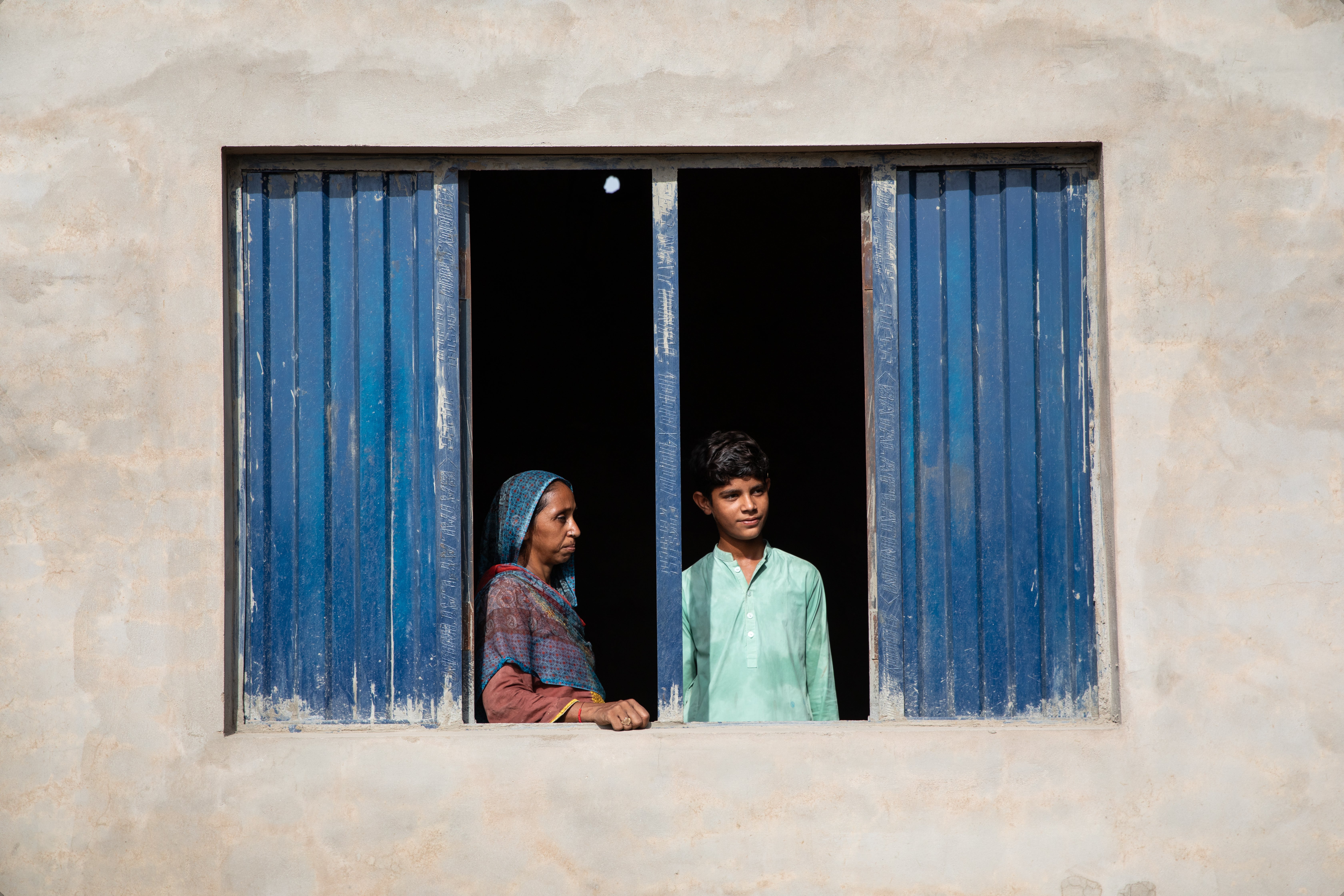 Zain, a 13-year-old boy from rural Pakistan, whose life is already impacted by 50°C heatwaves, and whose home was destroyed by devastating floods in 2022. He is pictured with his mum, Sughra, 35
