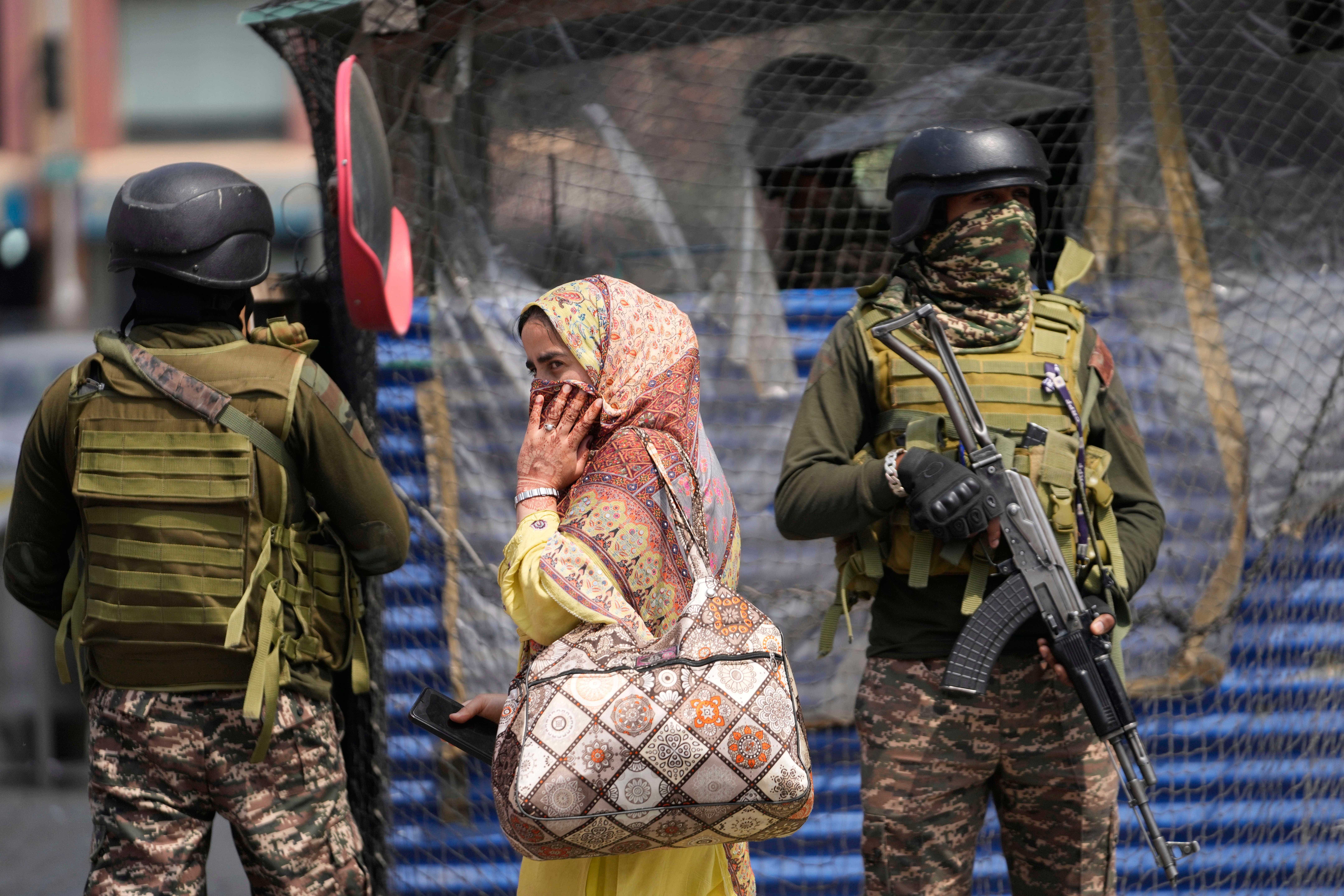 Indian soldiers stand guard as a woman walks in a market in Srinagar, Indian controlled Kashmir (AP Photo/Mukhtar Khan)