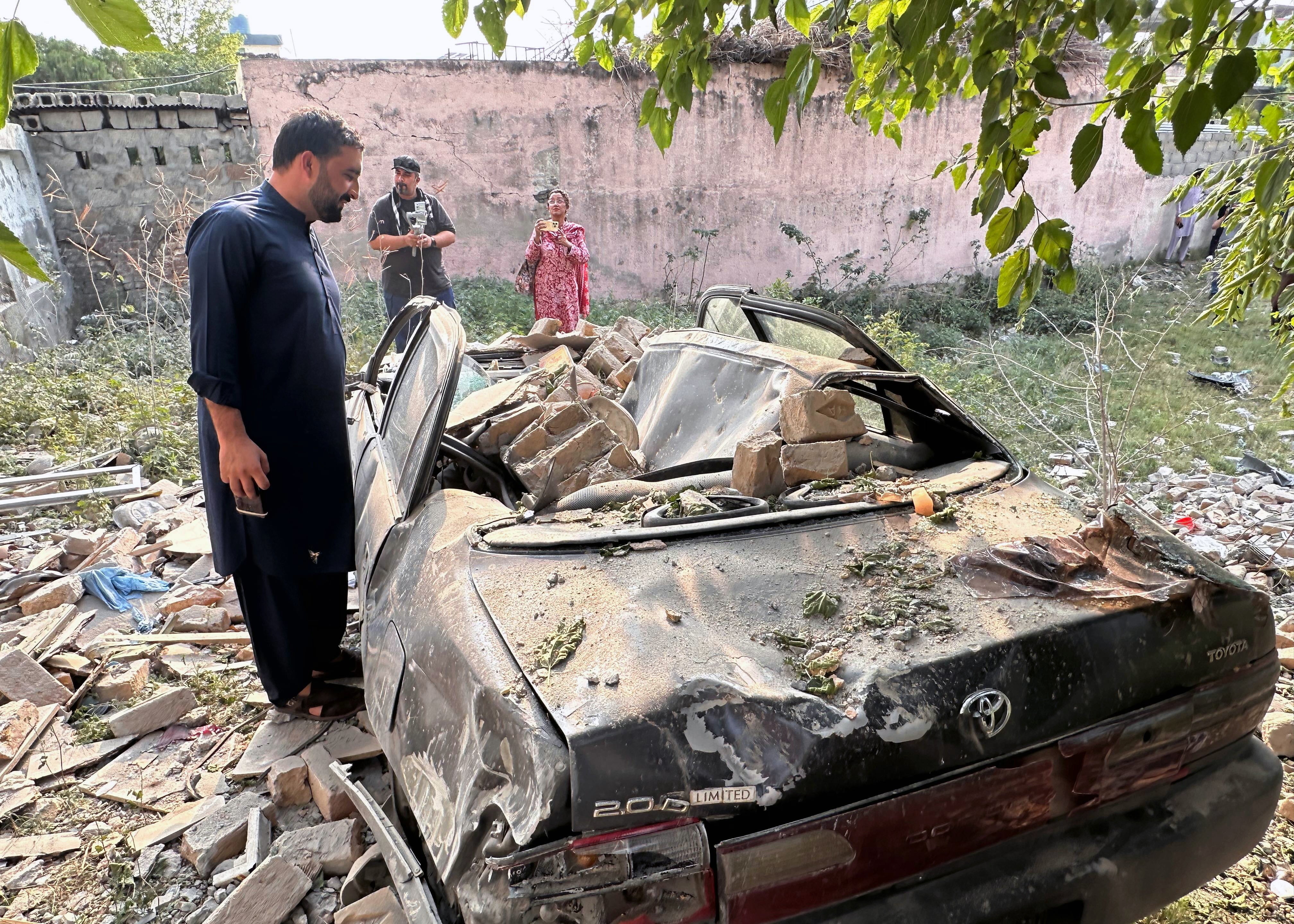 A man looks at a damaged car after Indian strikes in Kotli, Pakistan-administered Kashmir