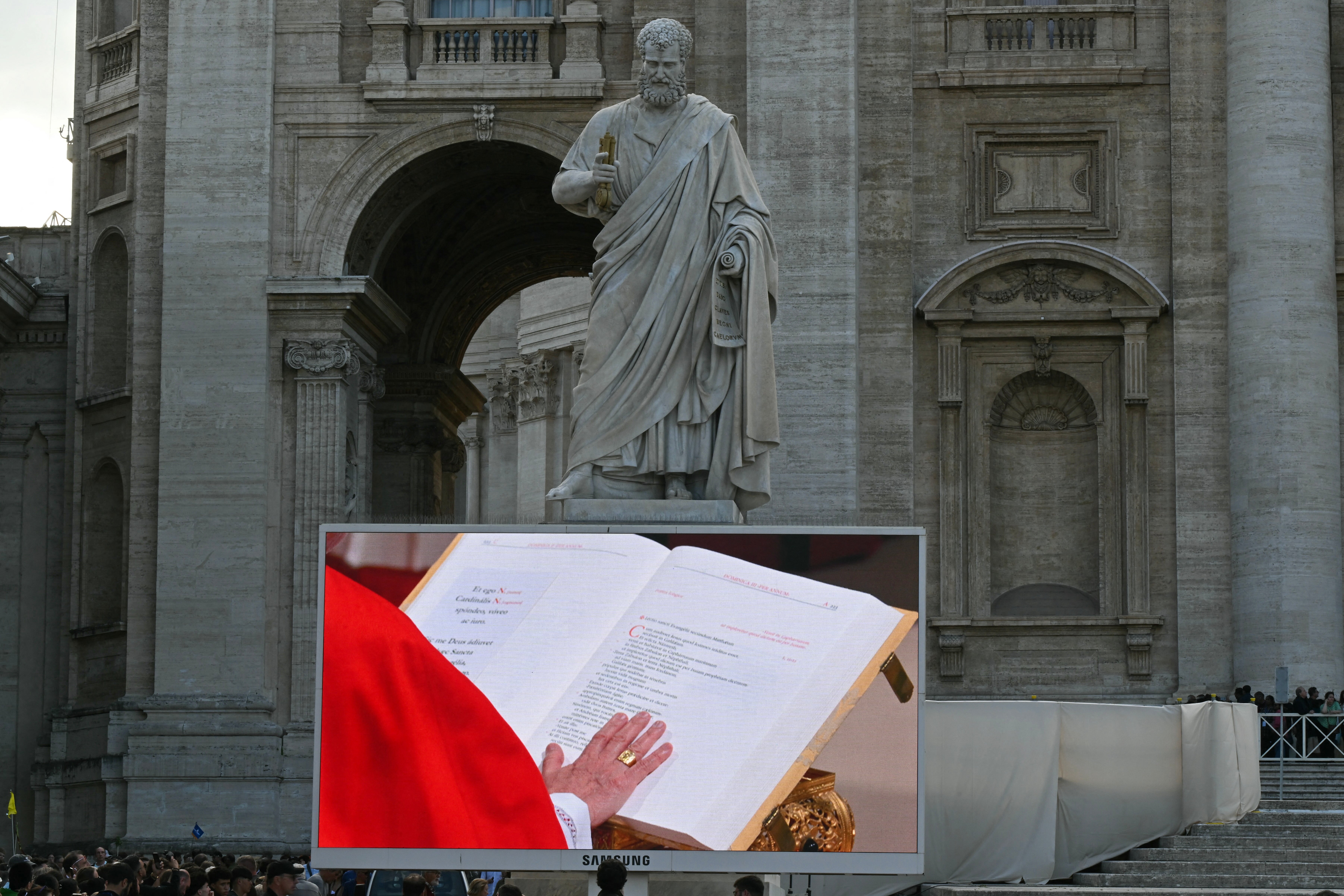 Faithful in St Peter’s Square watch a giant screen displaying a cardinal swearing his oath of secrecy