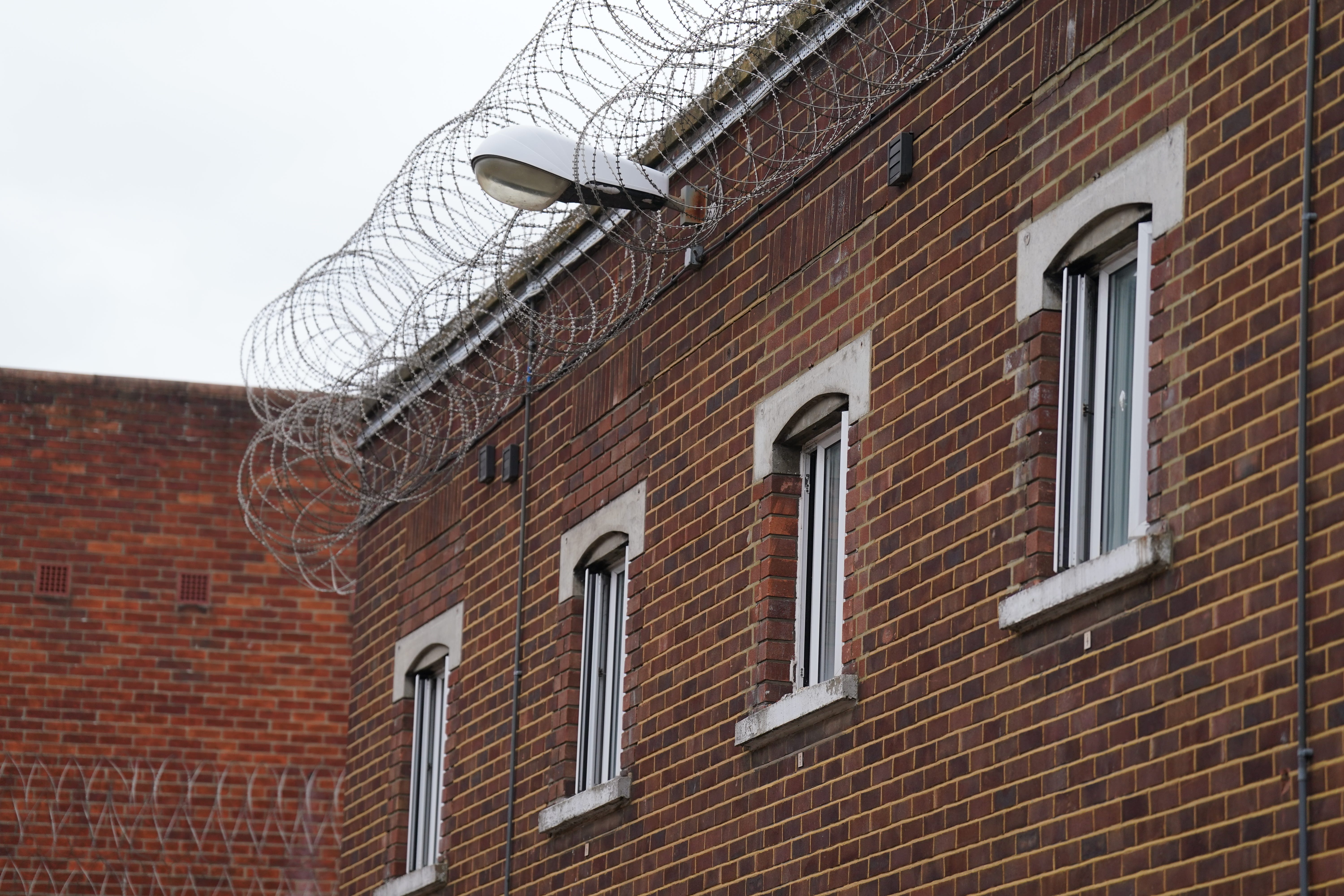Barbed wire and windows to cells on the walls of HMP Bedford (Joe Giddens/PA)