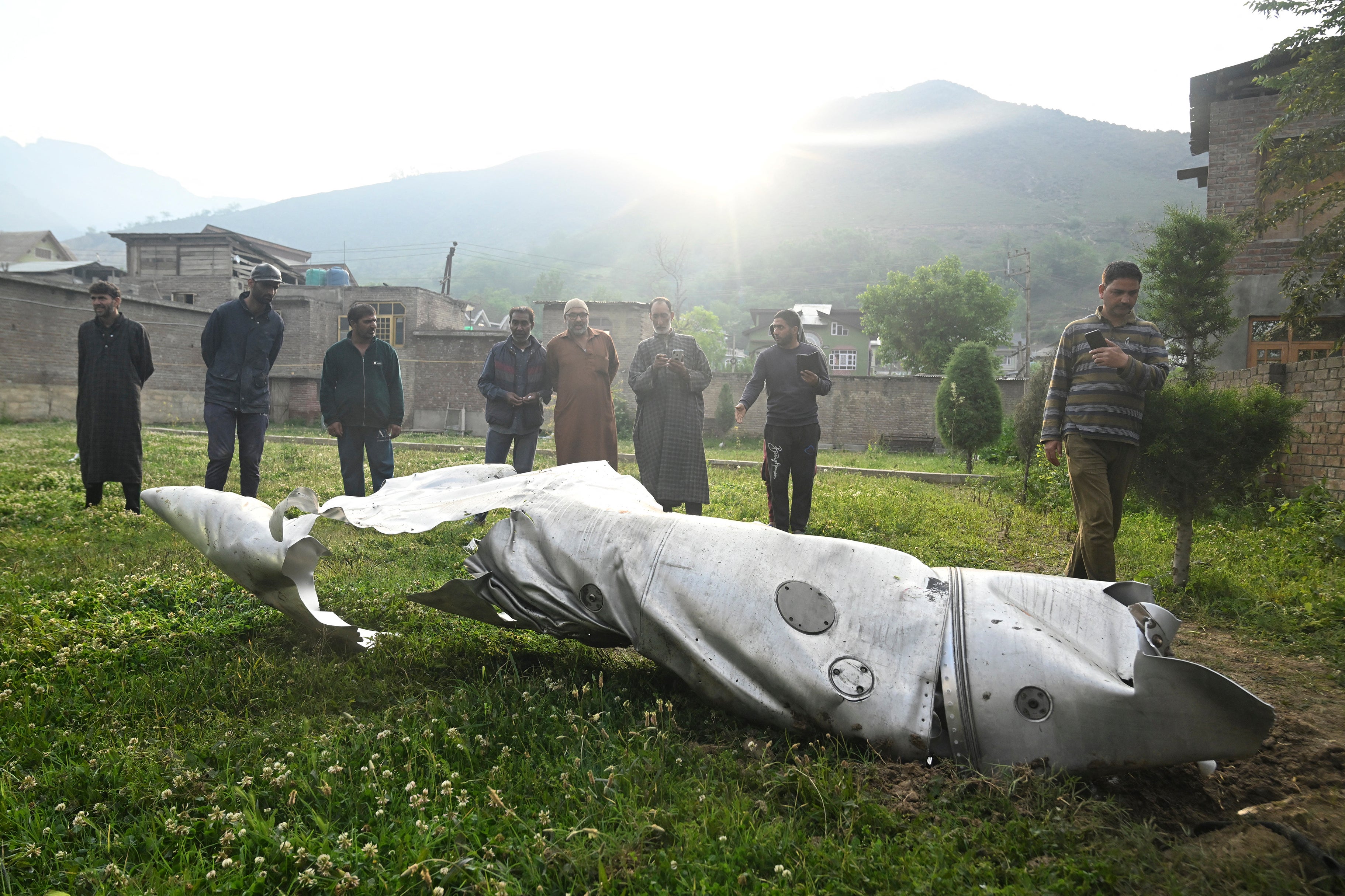 People look at a part of an aircraft in Wuyan near Indian-administered Kashmir's main city of Srinagar on 7 May 2025