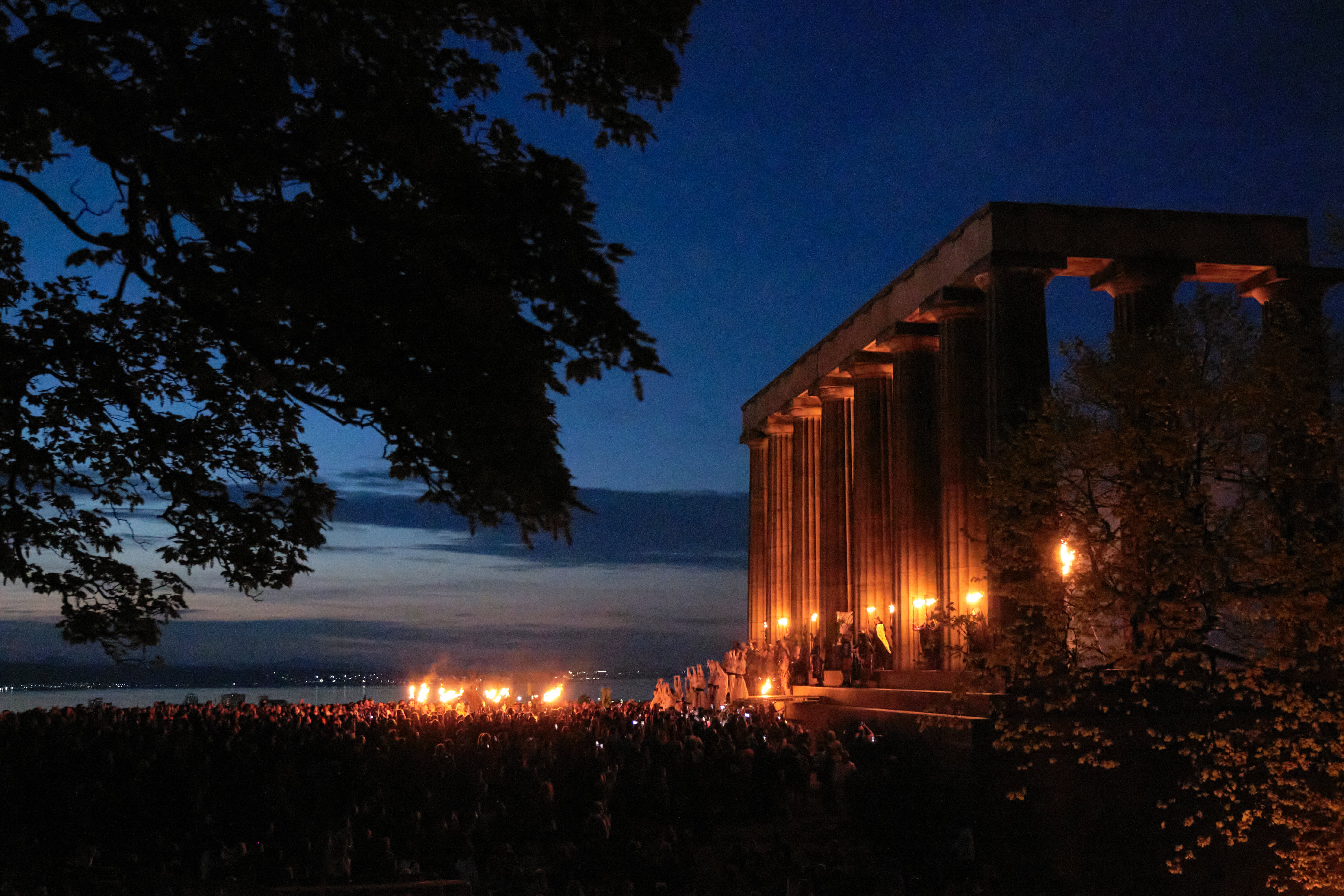 Torches aflame at sunset line The National Monument of Scotland