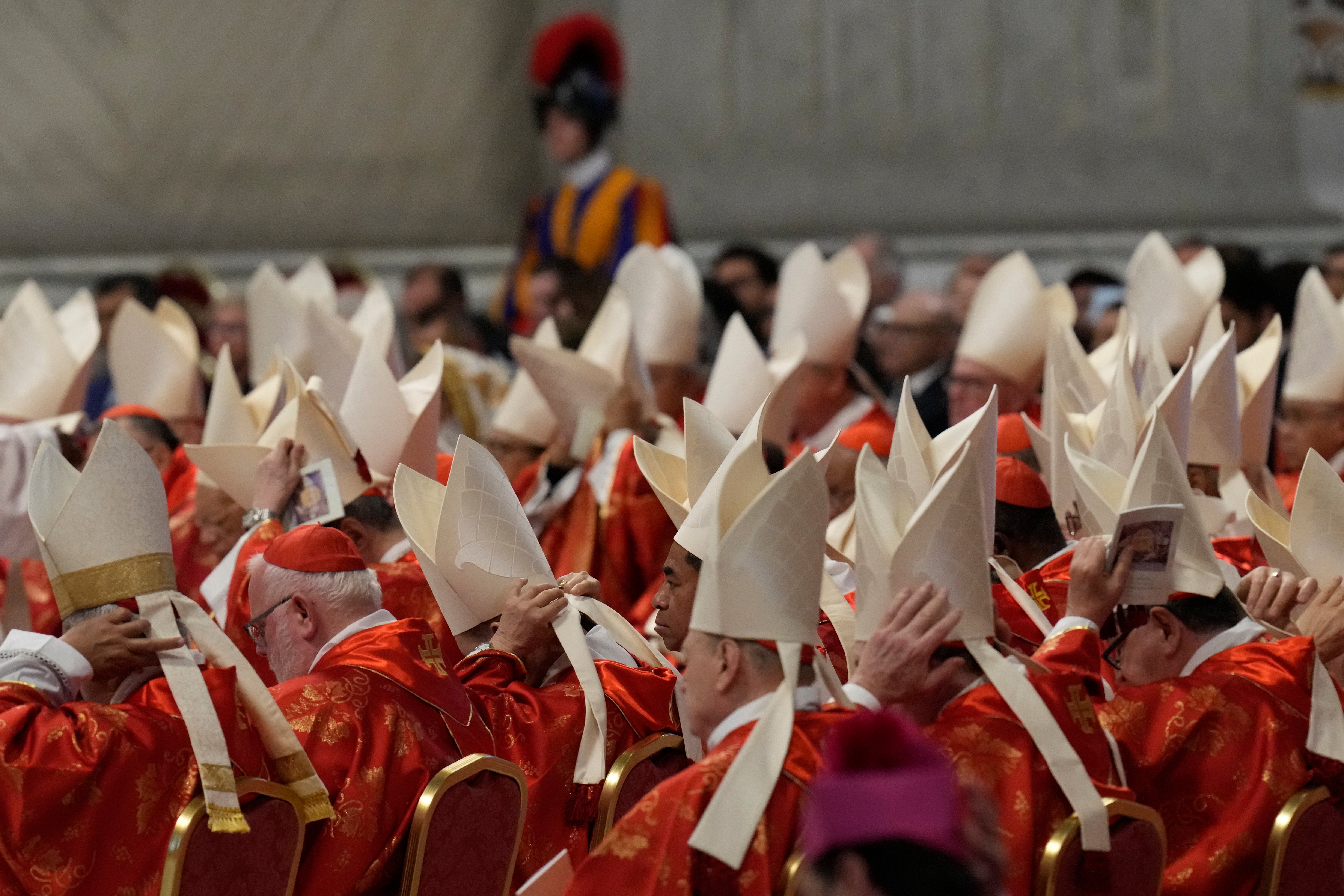 Cardinals adjust their mitre hats during a final Mass celebrated by cardinals inside St. Peter's Basilica before the conclave to elect a new pope, at the Vatican